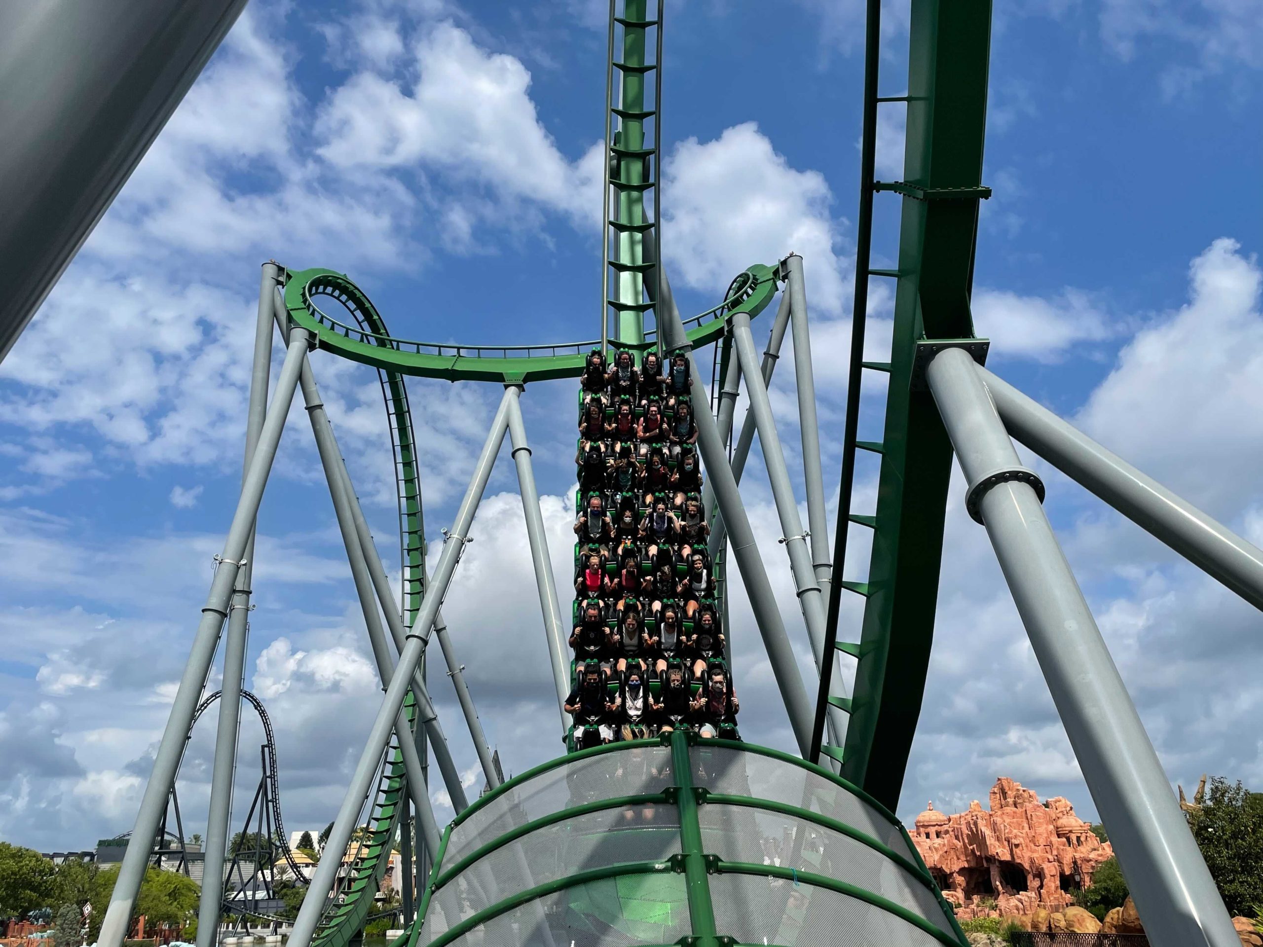 A full train on the green Incredible Hulk coaster swoops down into a transparent tunnel at Universal's Islands of Adventure.
