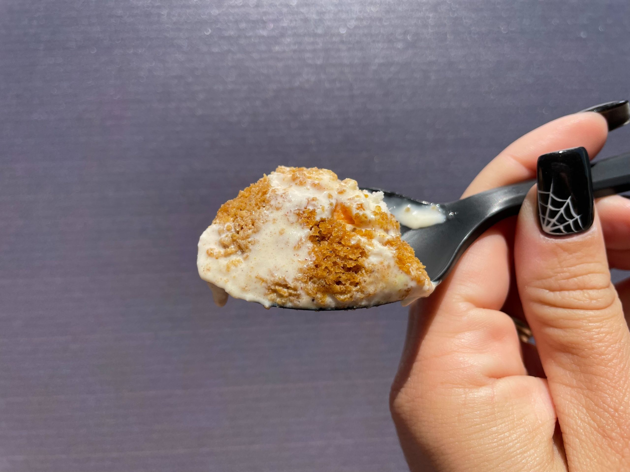 Spoon with a bite of Salt & Straw ice cream cup with a scoop of Jack o' Lantern pumpkin bread ice cream.