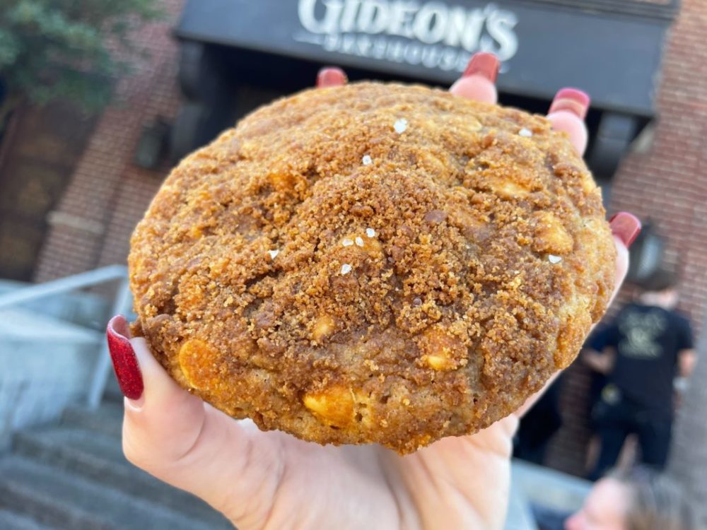 Light brown Cookie Butter Butterscotch Cookie held in front of Gideon's Bakehouse sign at Disney Springs