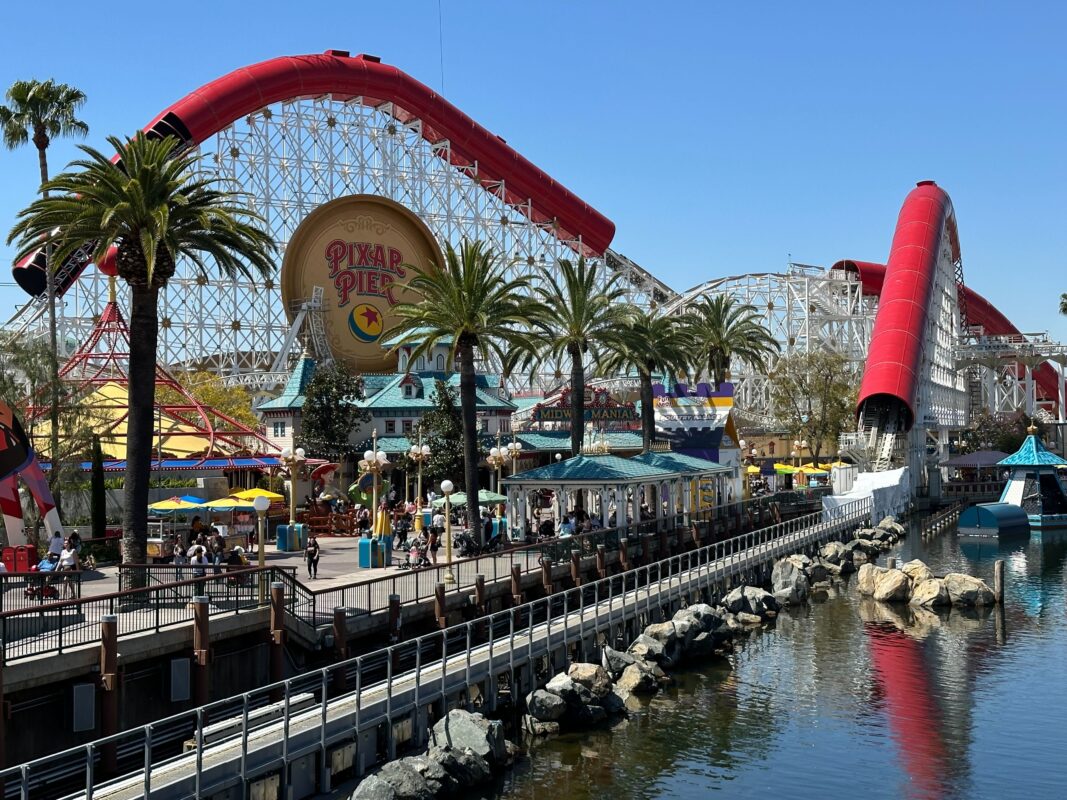 A section of the Incredicoaster goes over the water, with the track and Pixar Pier logo visible in the background.