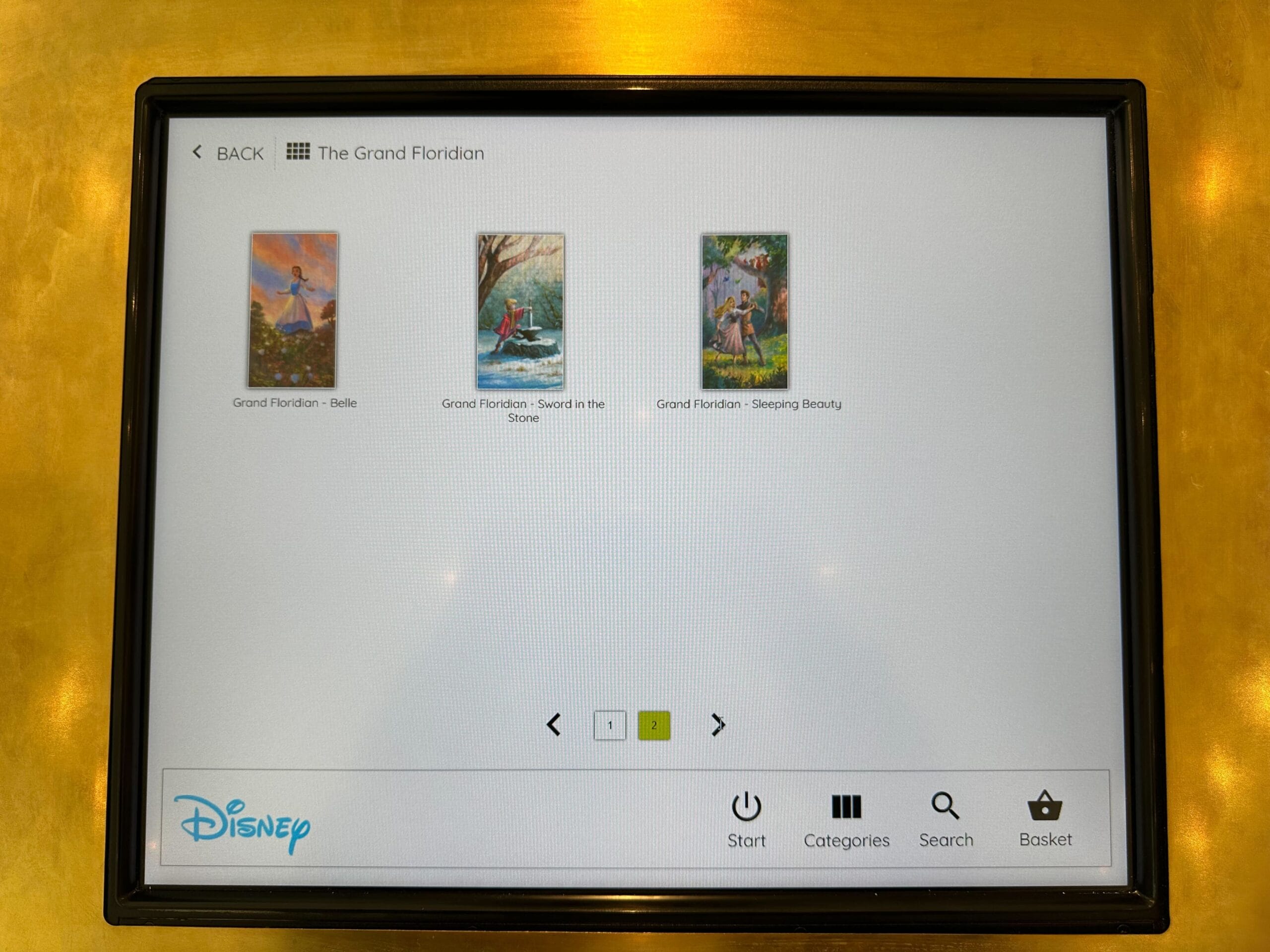 A digital display at the Grand Floridian showcases three stunning Disney artwork thumbnails: Belle, Sword in the Stone, and Sleeping Beauty. Experience art on demand with menu options like start, categories, search, and basket for seamless navigation.