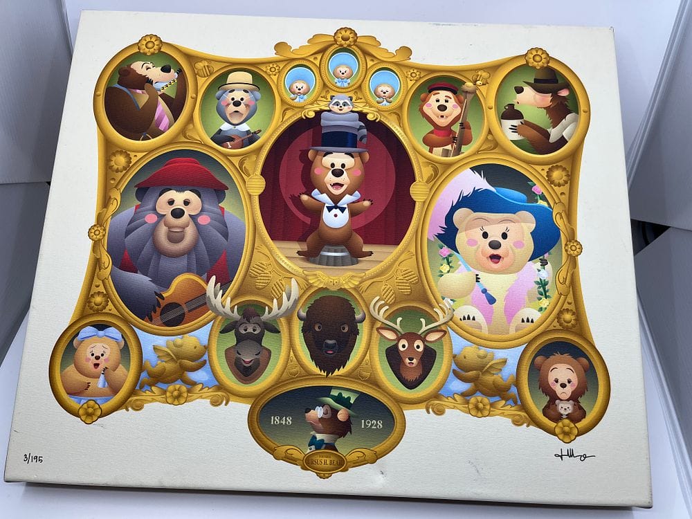 Framed artwork featuring various bears in colorful attire, with musical themes. The central bear wears a top hat. The frame has ornate golden decorations and the years 1848 and 1928, making it a centerpiece for the upcoming Spring Cleaning Auction in 2025.