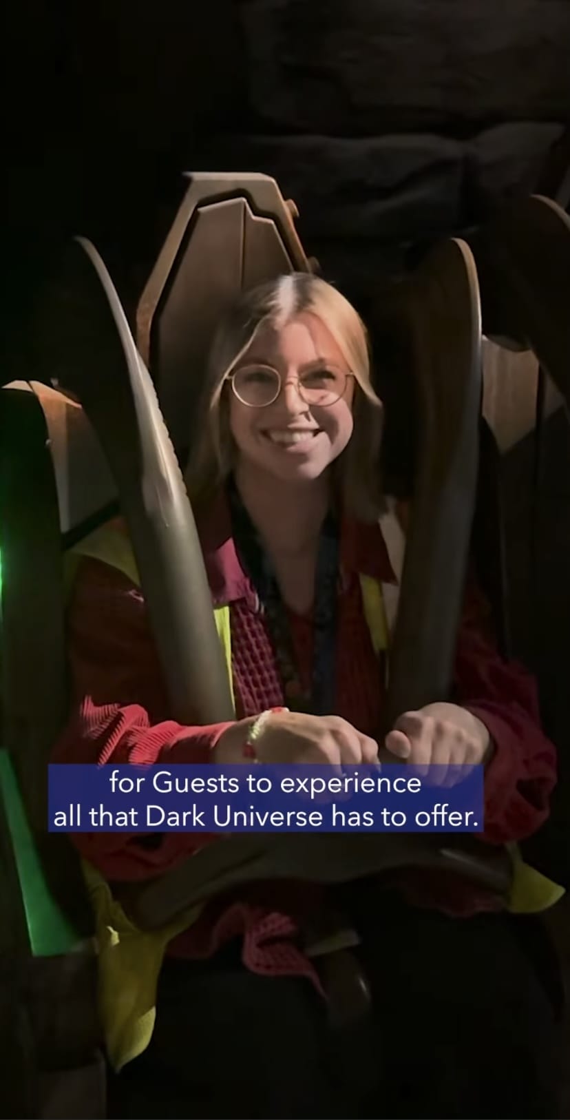 Person seated on a themed amusement ride with a sign that reads, "for Guests to experience all that Dark Universe has to offer.