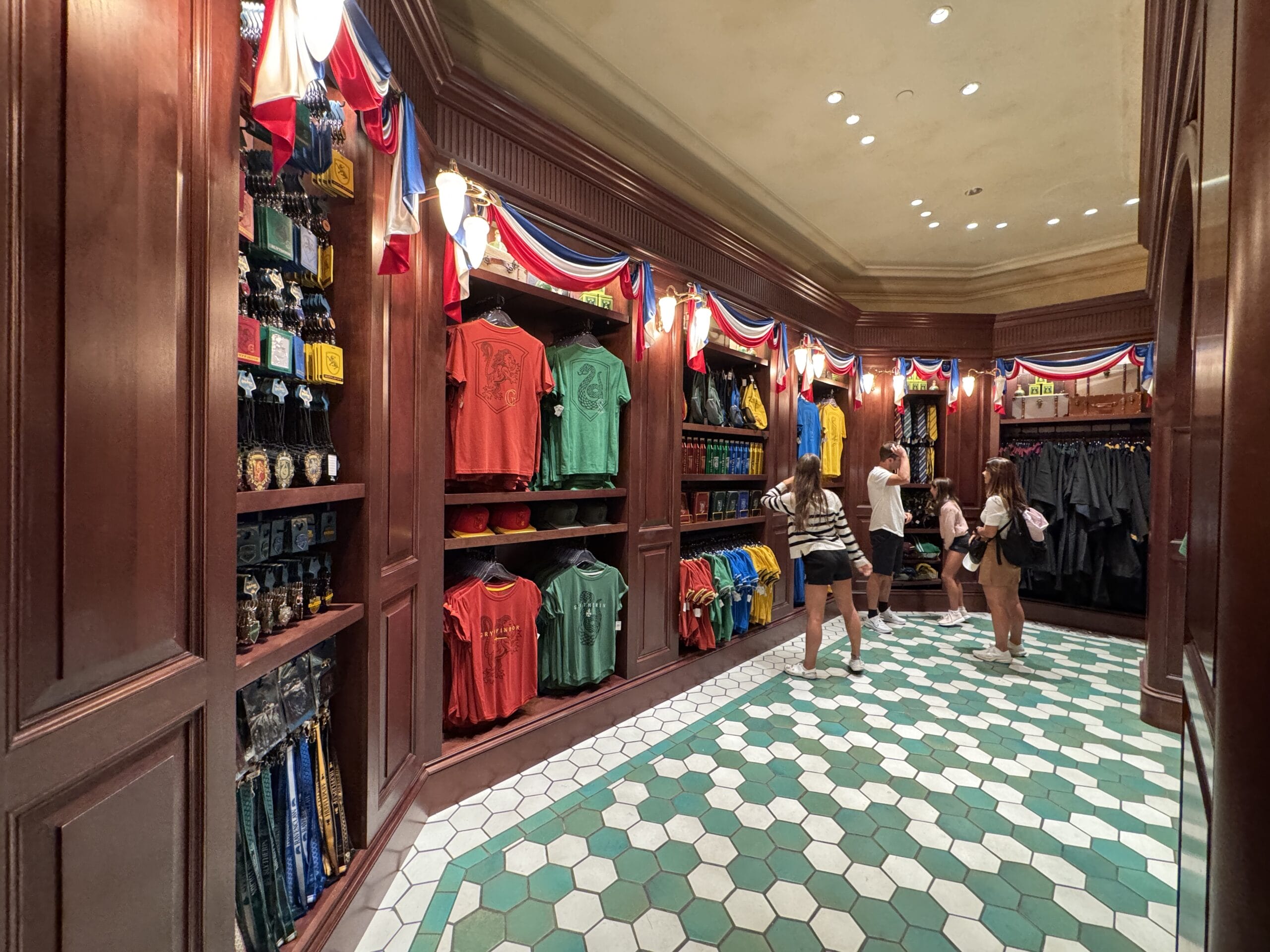 Three women shop at Tour En Floo Shop, browsing shirts and souvenirs in this Wizarding World of Harry Potter store.