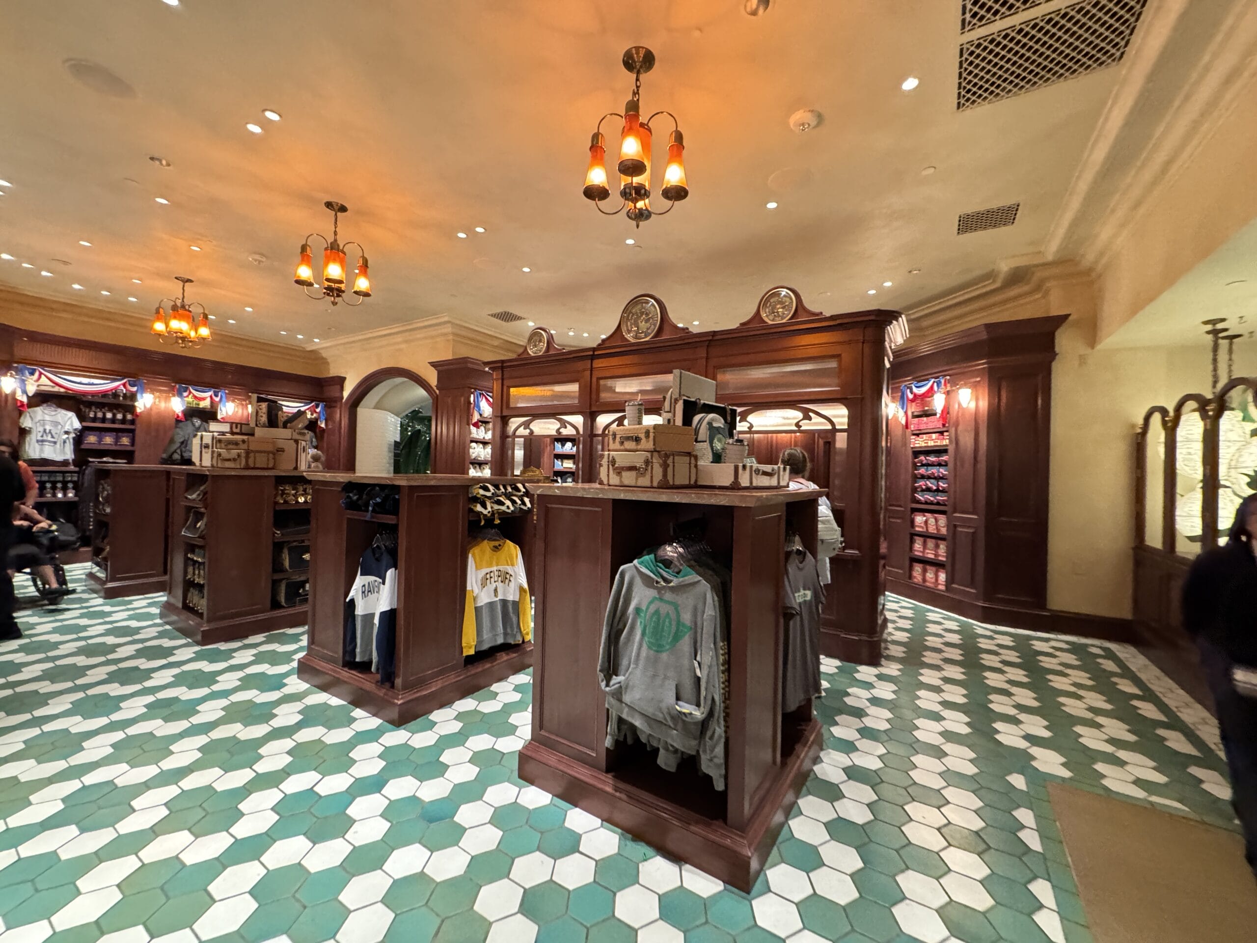 Clothing store with wooden shelves, tiled floor, and hanging lights—just steps from Epic Universe’s Tour En Floo Shop.