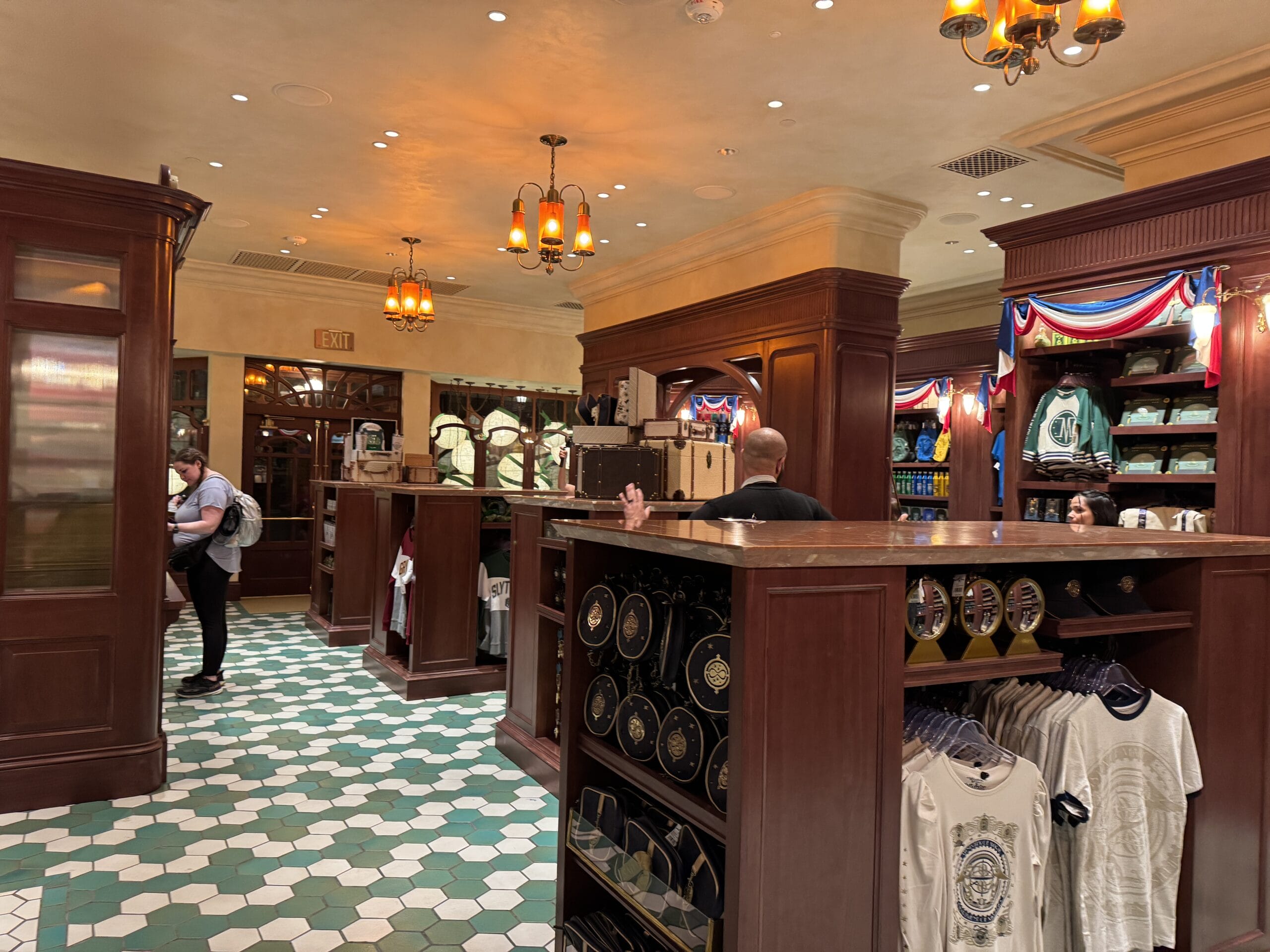 A store interior at Tour En Floo Shop with wooden shelves, souvenirs, and shoppers in the Wizarding World of Harry Potter.