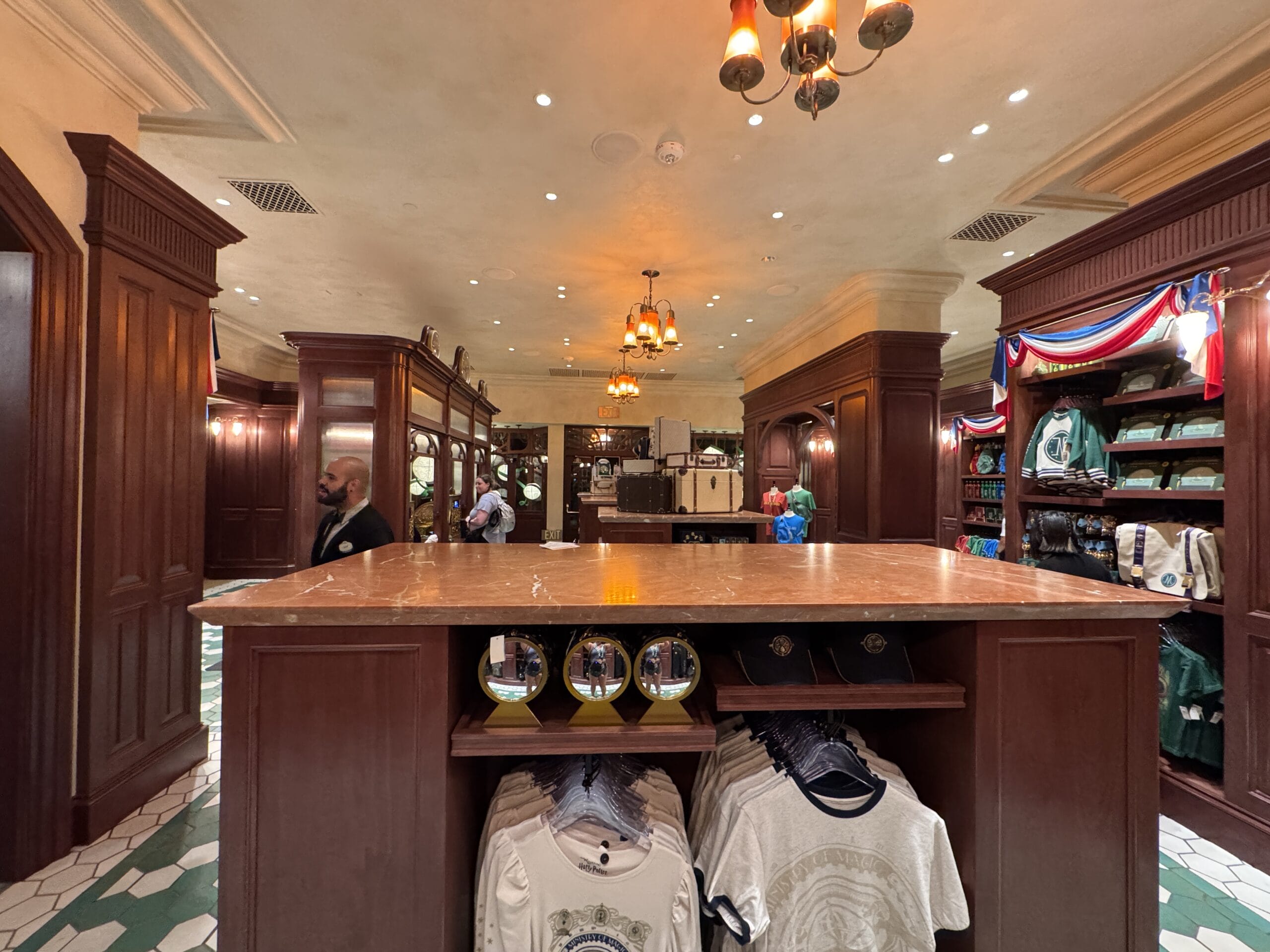 A clothing and souvenir shop at Epic Universe with wood décor, hanging lights, and Wizarding World of Harry Potter merchandise.