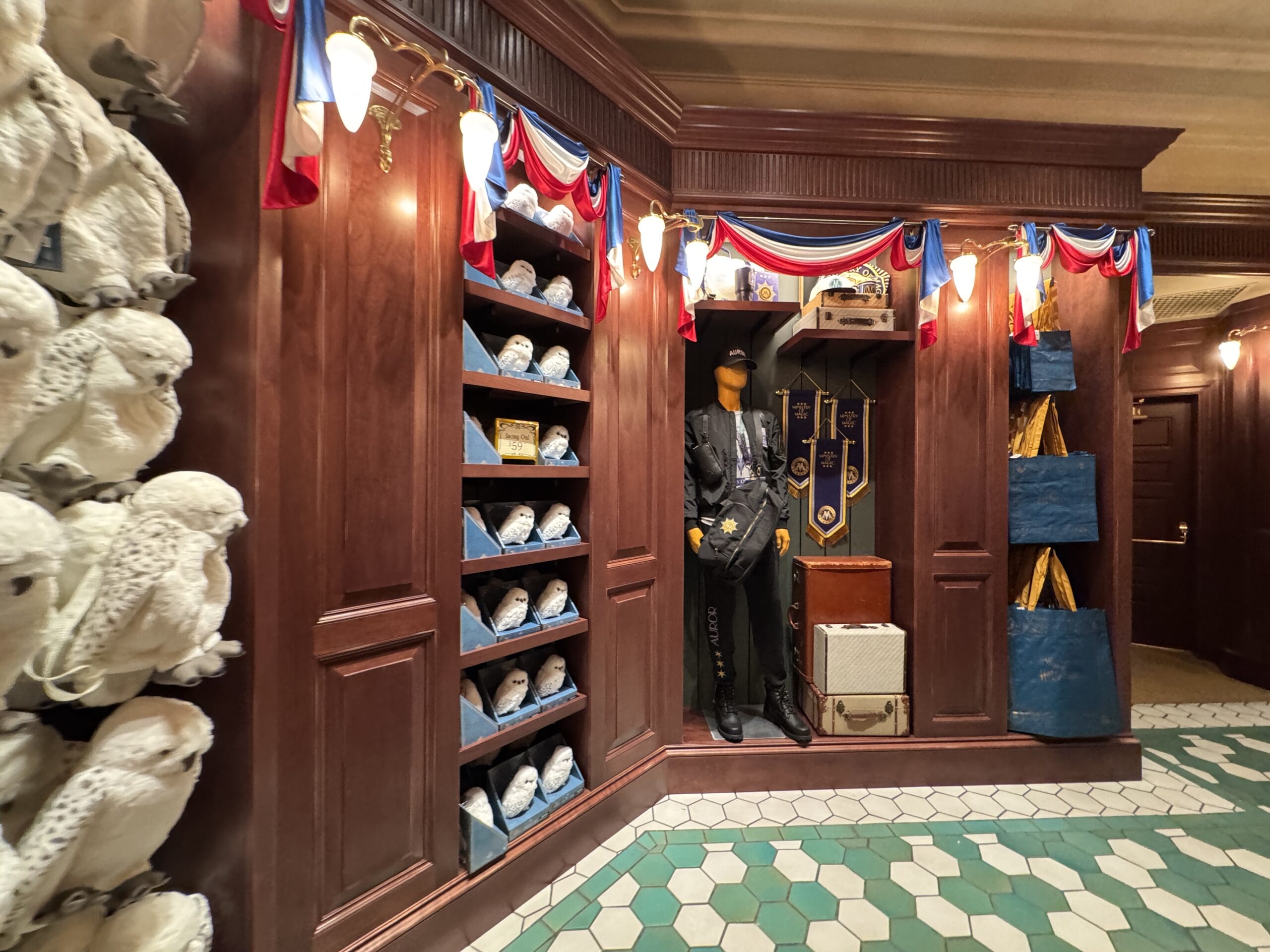 Wood-paneled room at Tour En Floo Shop with owl plushies, school uniform display, and blue bags on the right.