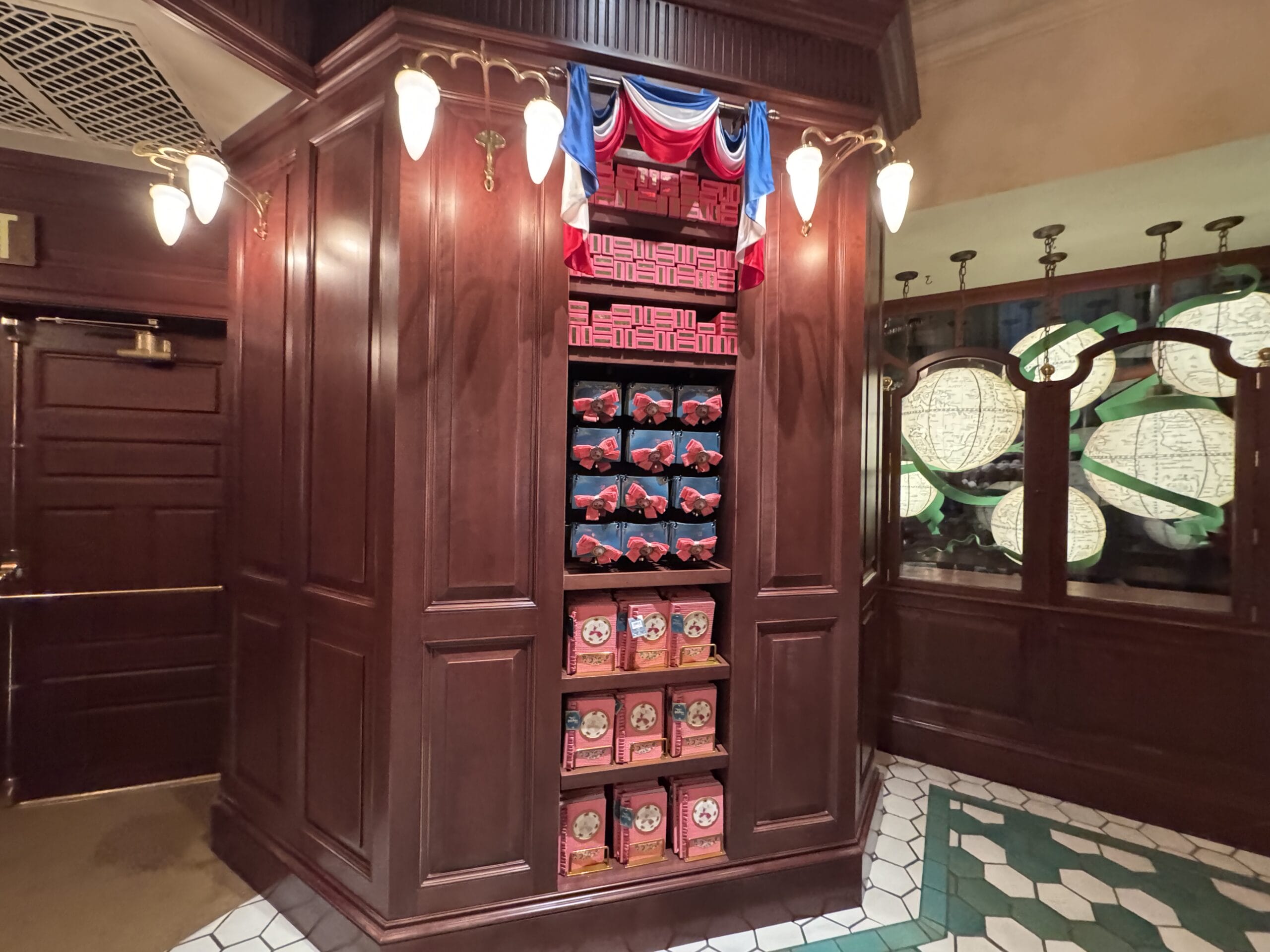 A wooden display shelf at Tour En Floo Shop holds themed merchandise in the warmly lit Wizarding World of Harry Potter.