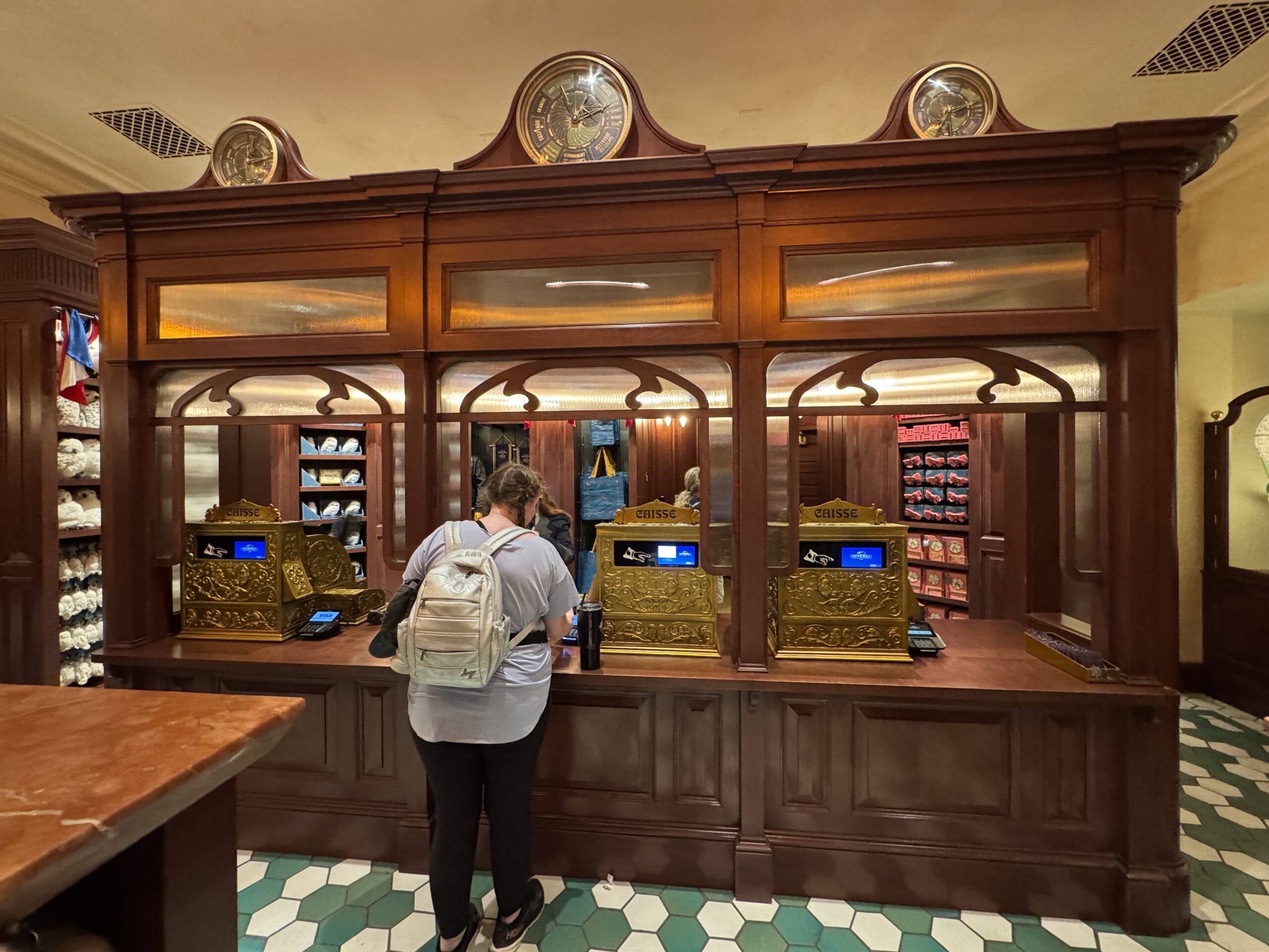 A person with a backpack stands at a vintage counter in the Wizarding World of Harry Potter’s Tour En Floo Shop.