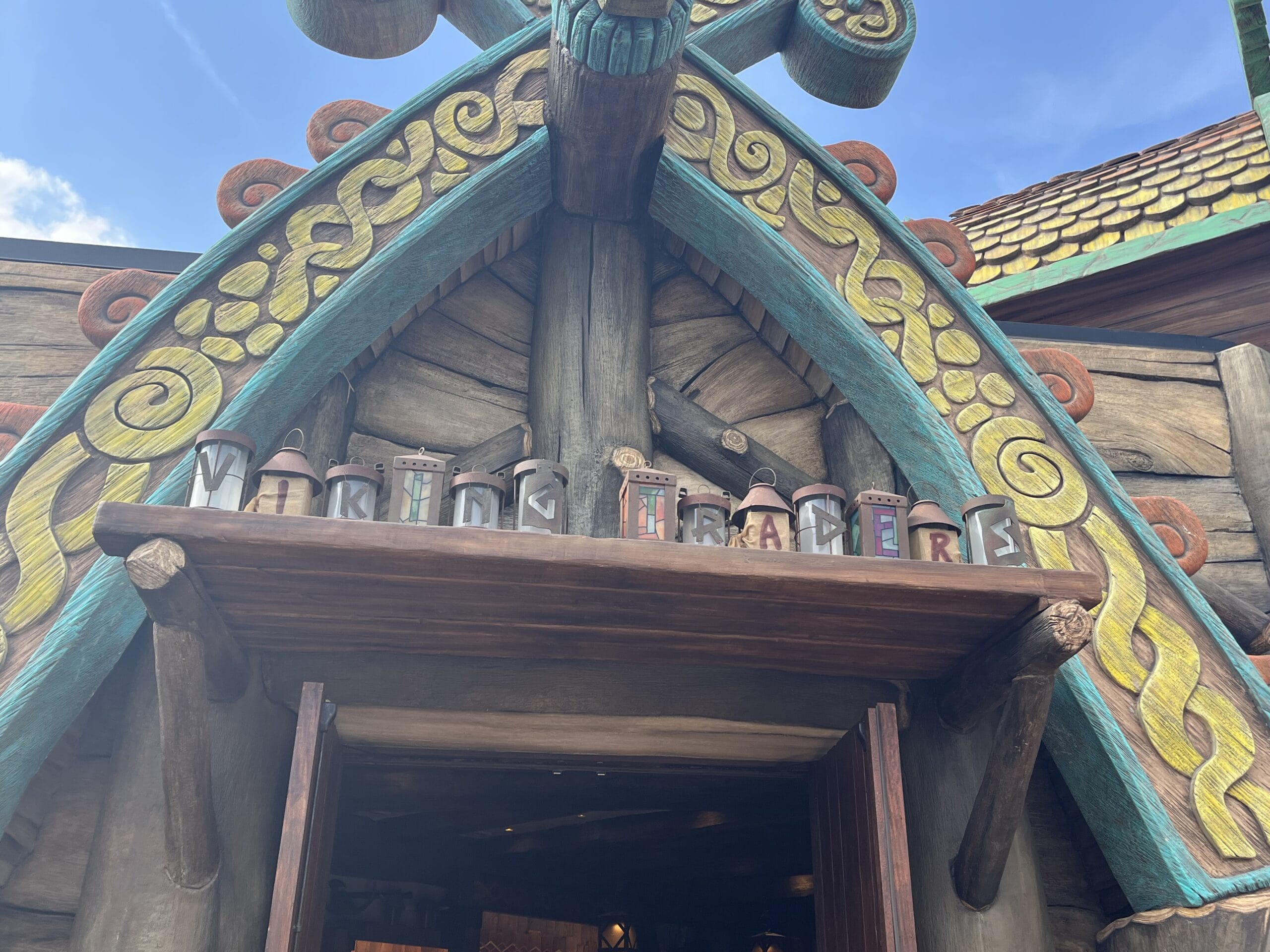 Vibrant wooden shop facade at Epic Universe with lanterns above the entrance spelling out "Viking Traders.