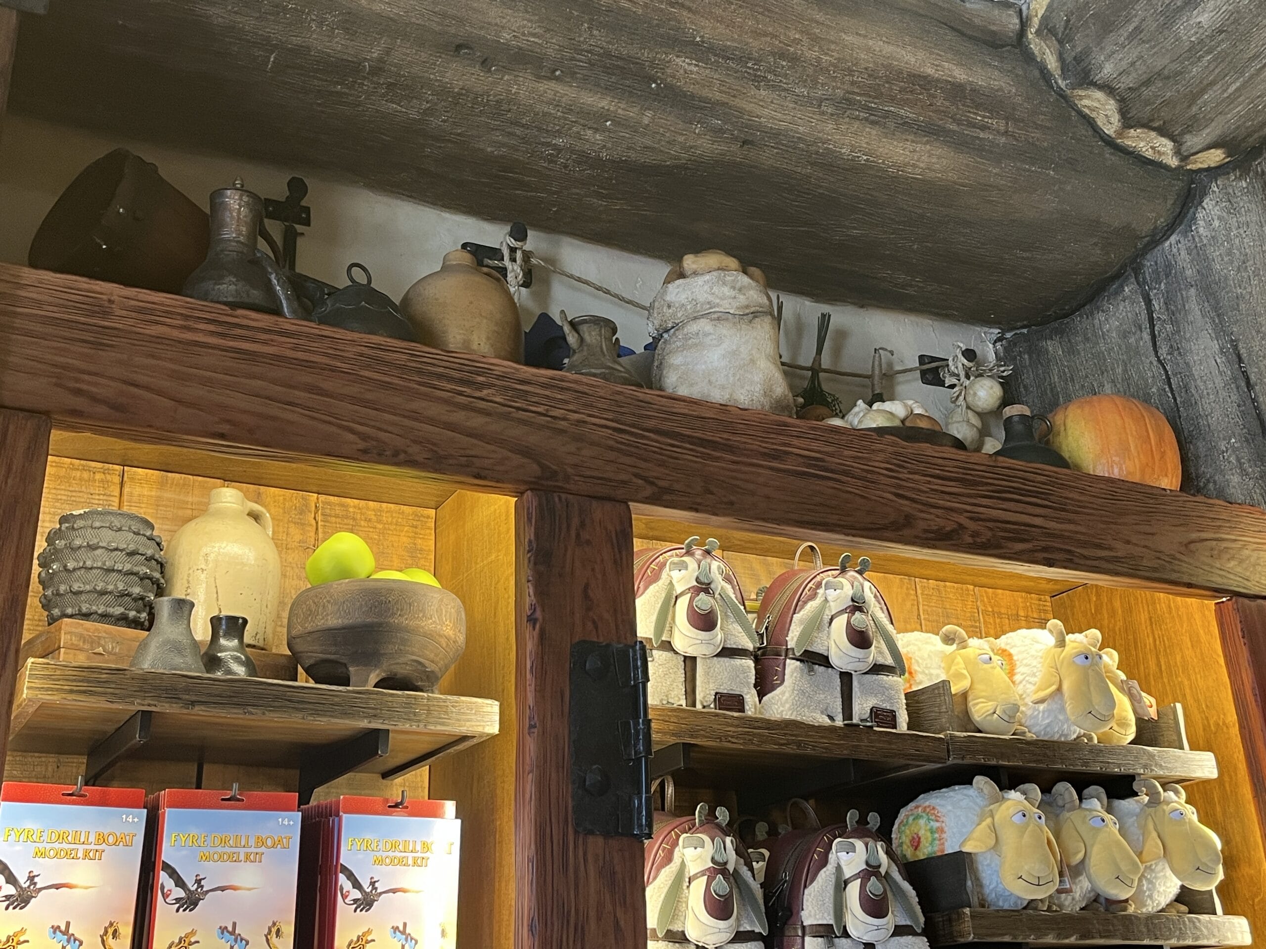 Wooden shelves at Viking Traders show vintage pottery, an apple, plush donkey toys, books, and trinkets in a park shop display.