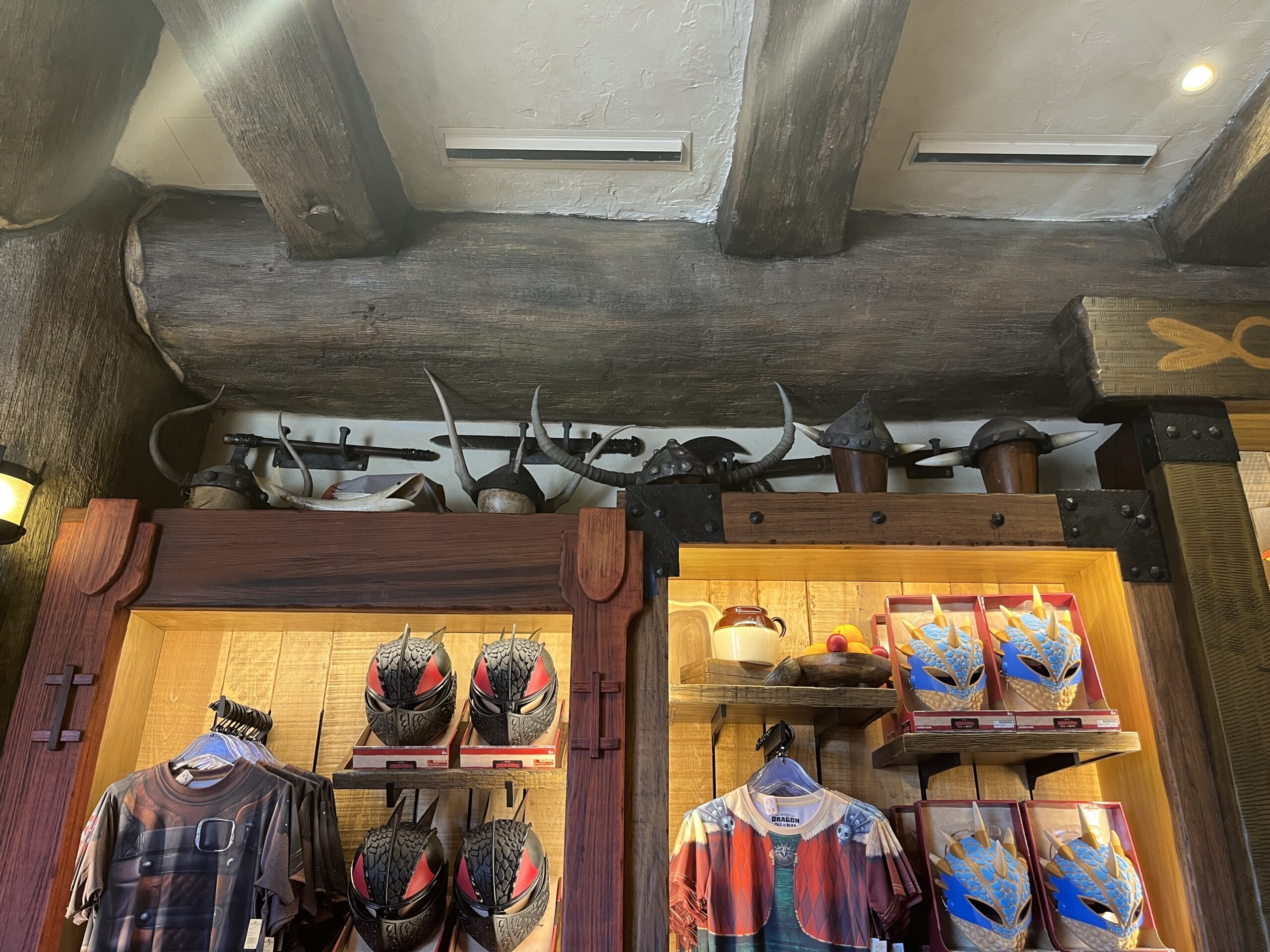 Viking Traders helmets and shields above shelves of Hiccup and Astrid merchandise in a park-themed store.
