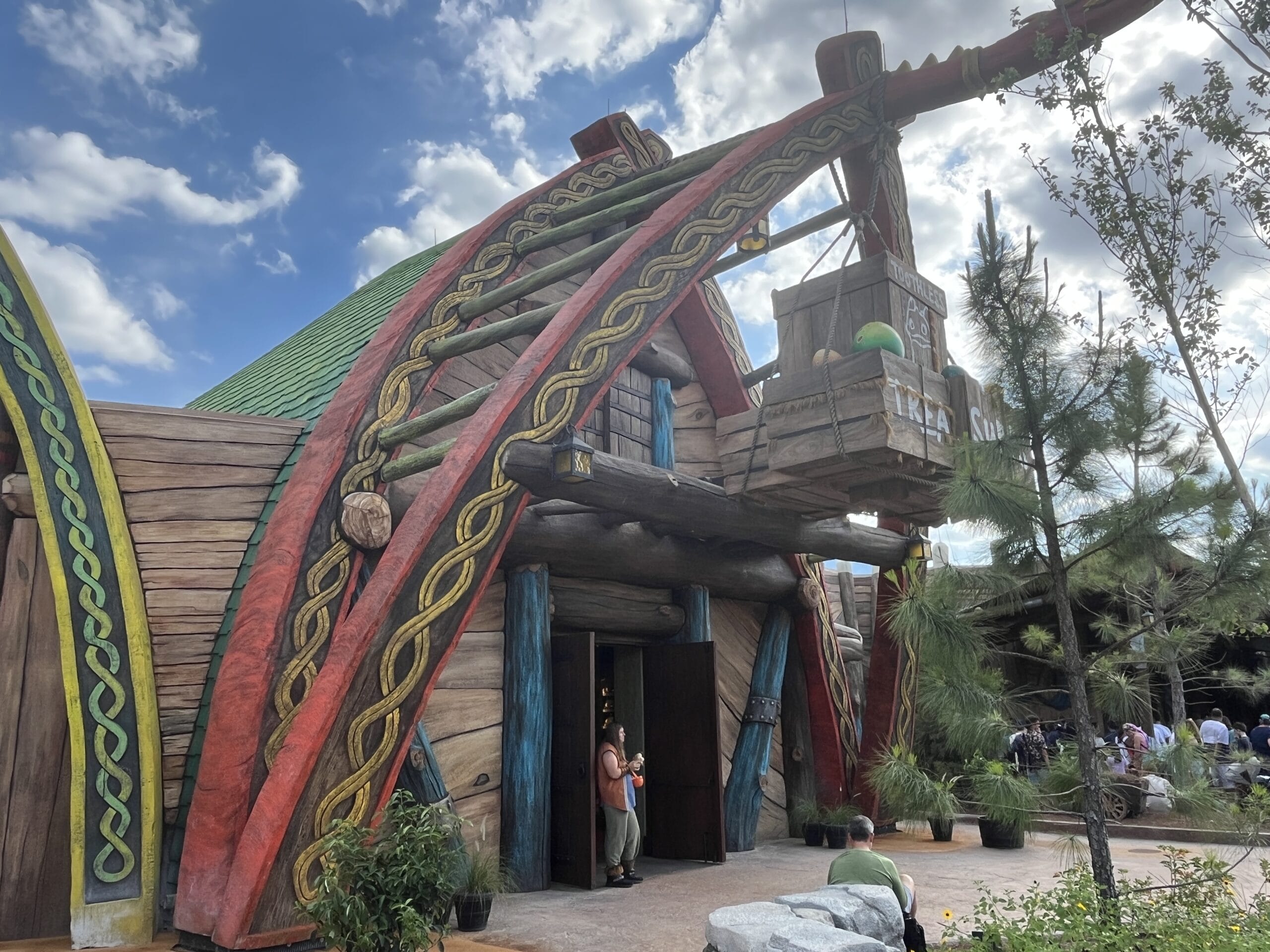 A rustic, Viking-style building with carved wooden details houses Toothless' Treasures beneath a partly cloudy sky.