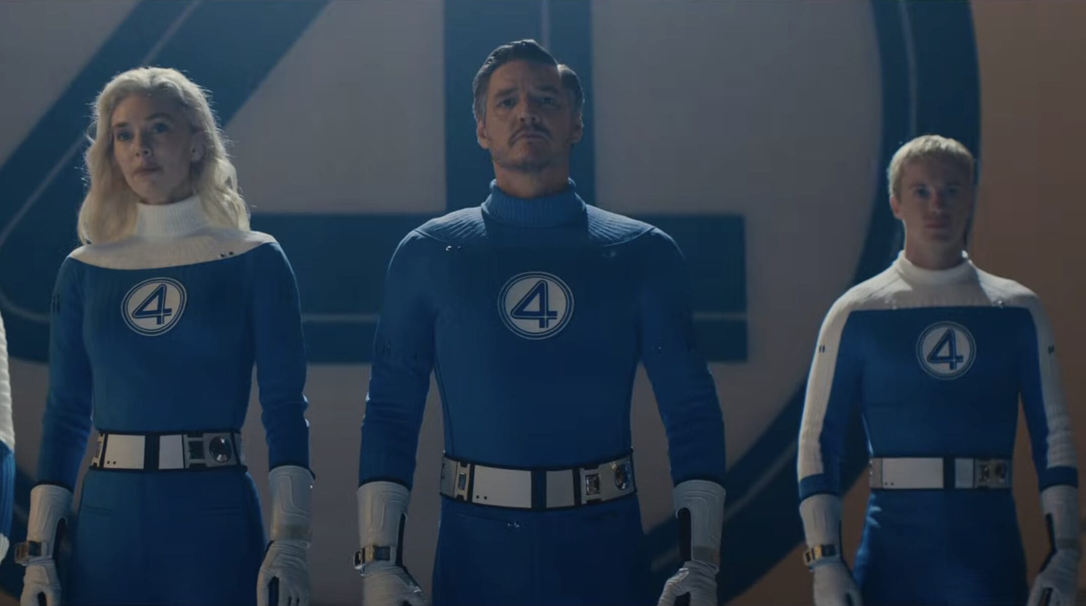 Three Fantastic Four look-alikes in blue suits stand side by side at Disneyland Resort, facing forward with serious expressions.