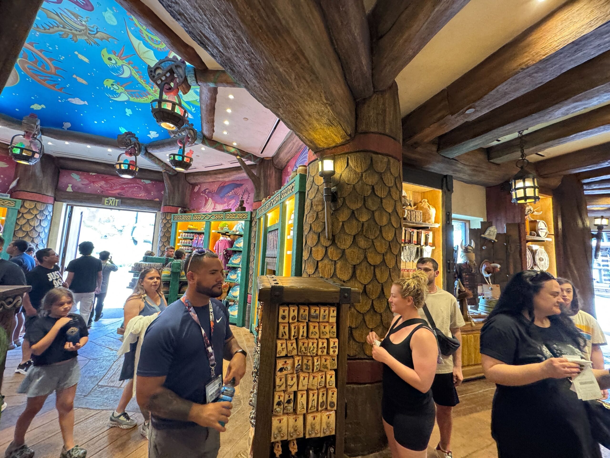 Guests browse inside Viking Traders, a vibrant shop with wood accents and an ocean-themed ceiling.