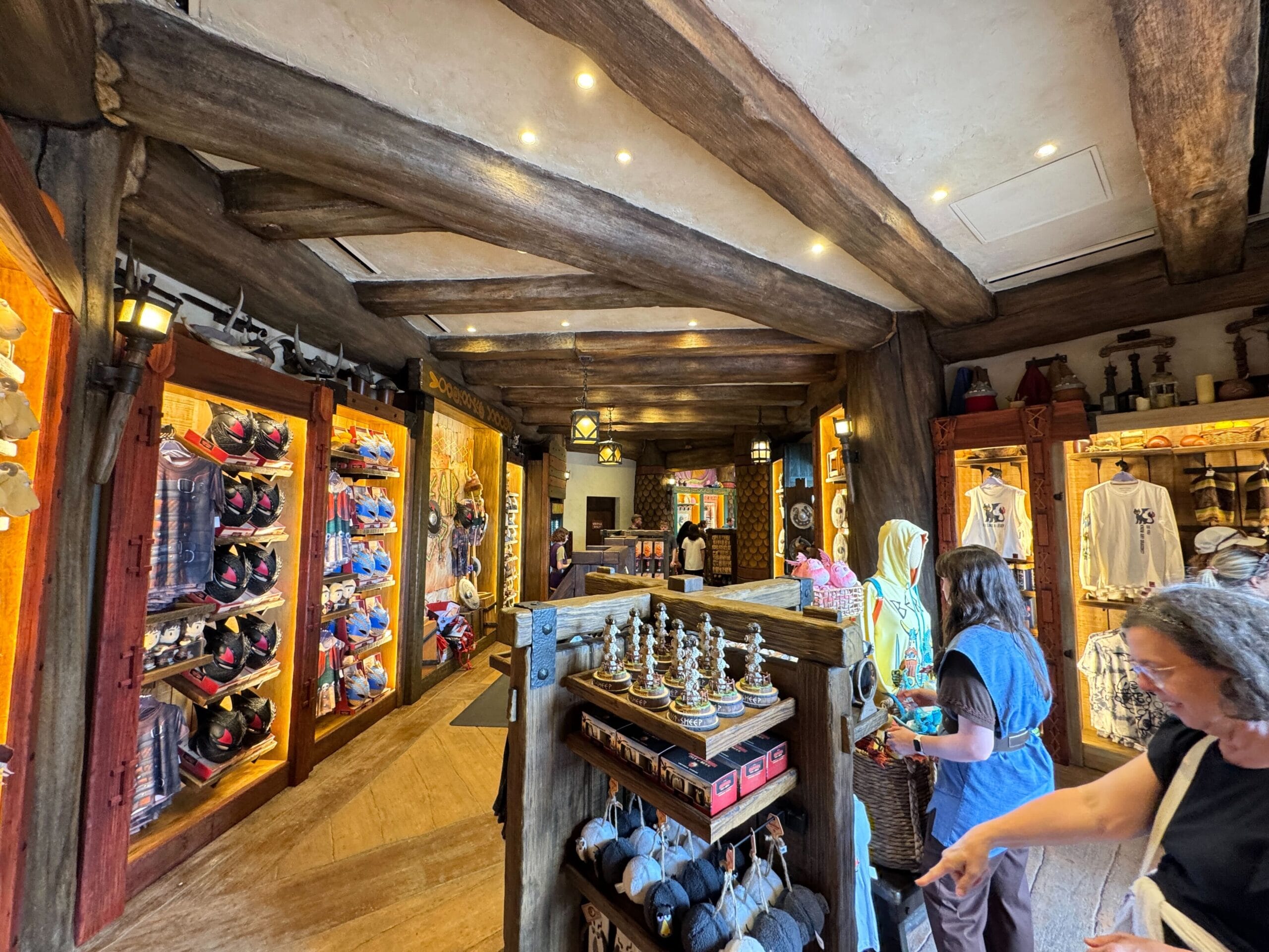 A Viking Traders gift shop at Epic Universe, with wooden beams, hats, shirts, souvenirs, and guests browsing inside.