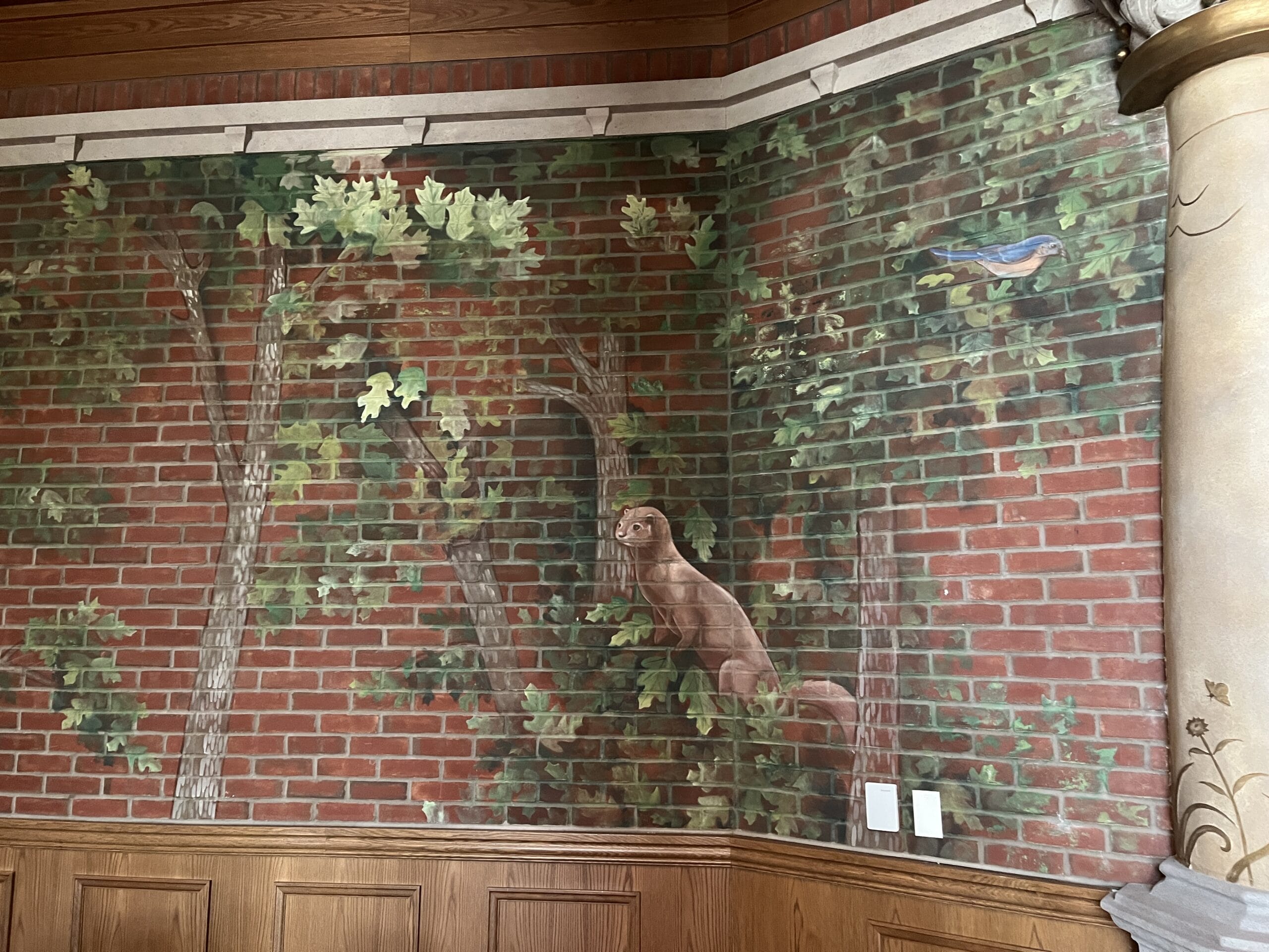 A whimsical mural at The Oak & Star Tavern features trees, leaves, a bird, and an otter, evoking a cozy, storybook Disney vibe.