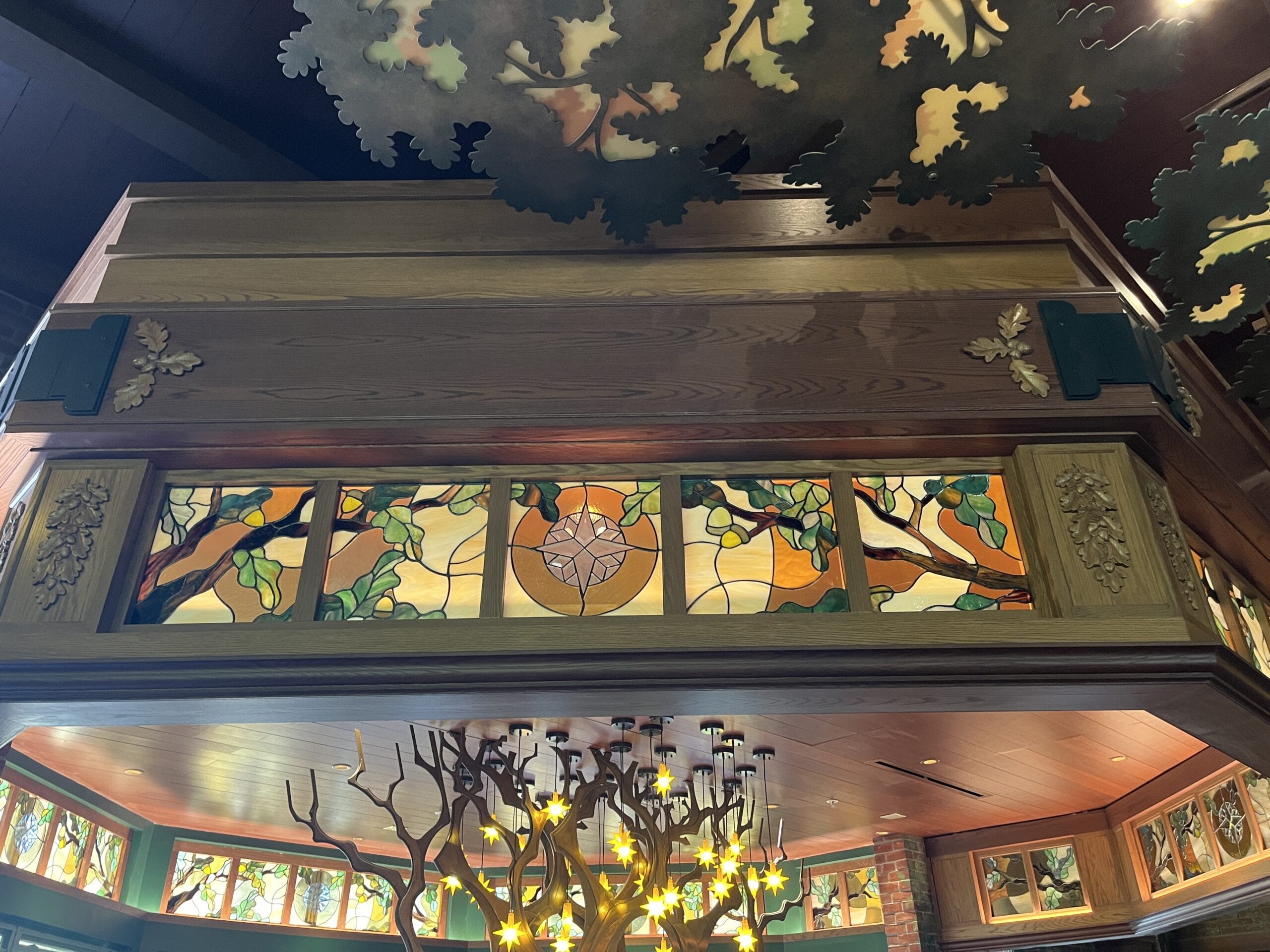 Stained glass panels with tree and leaf designs at The Oak & Star Tavern, their detail reminiscent of the artistry seen in Disney parks.