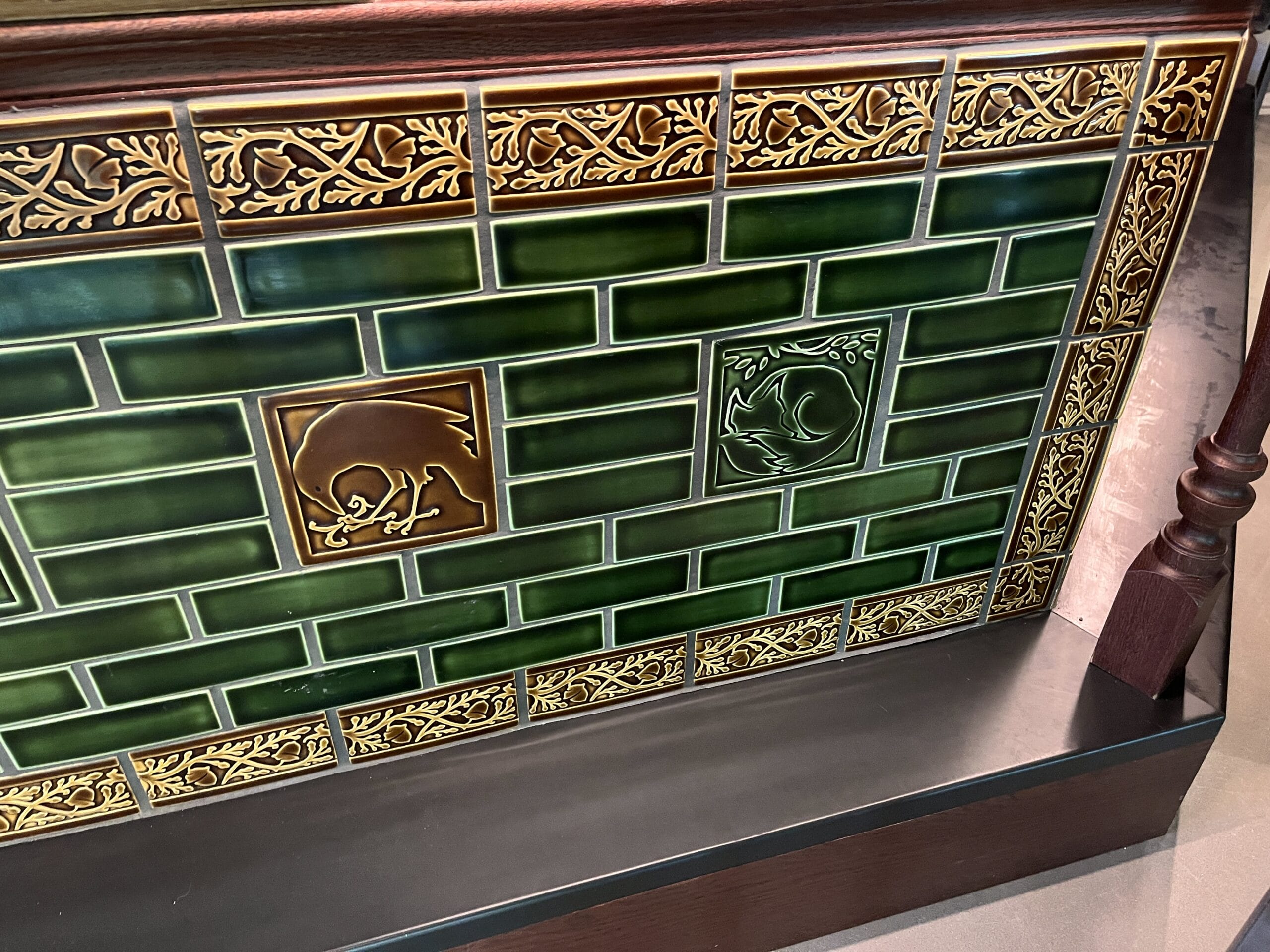 Elegant green-tiled fireplace with gold trim at The Oak & Star Tavern, featuring animal center tiles, not like Disney castle decor.