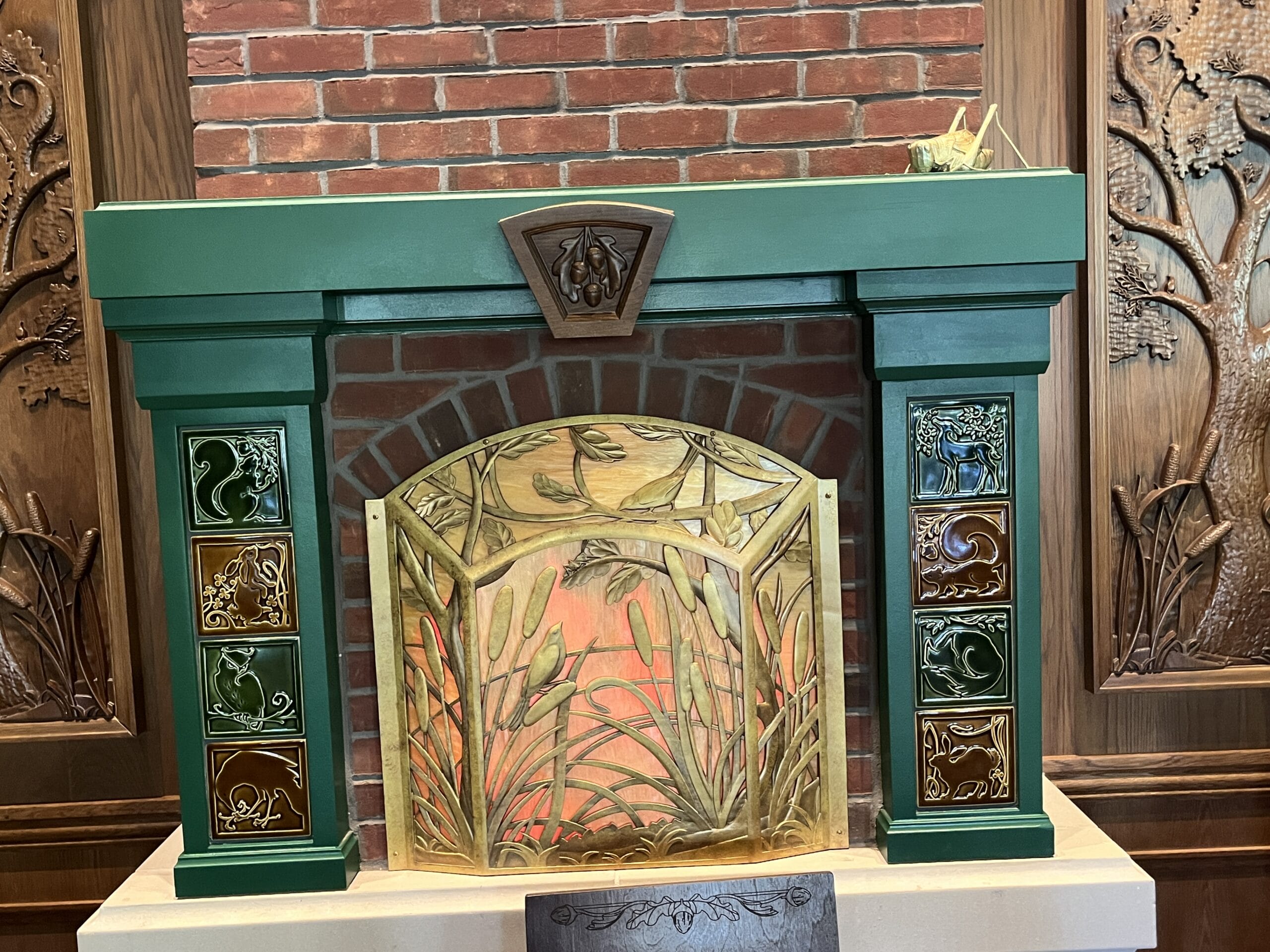 Green fireplace mantel with animal tiles at The Oak & Star Tavern, set among red brick and wood paneling, cozy as a Disney lodge.
