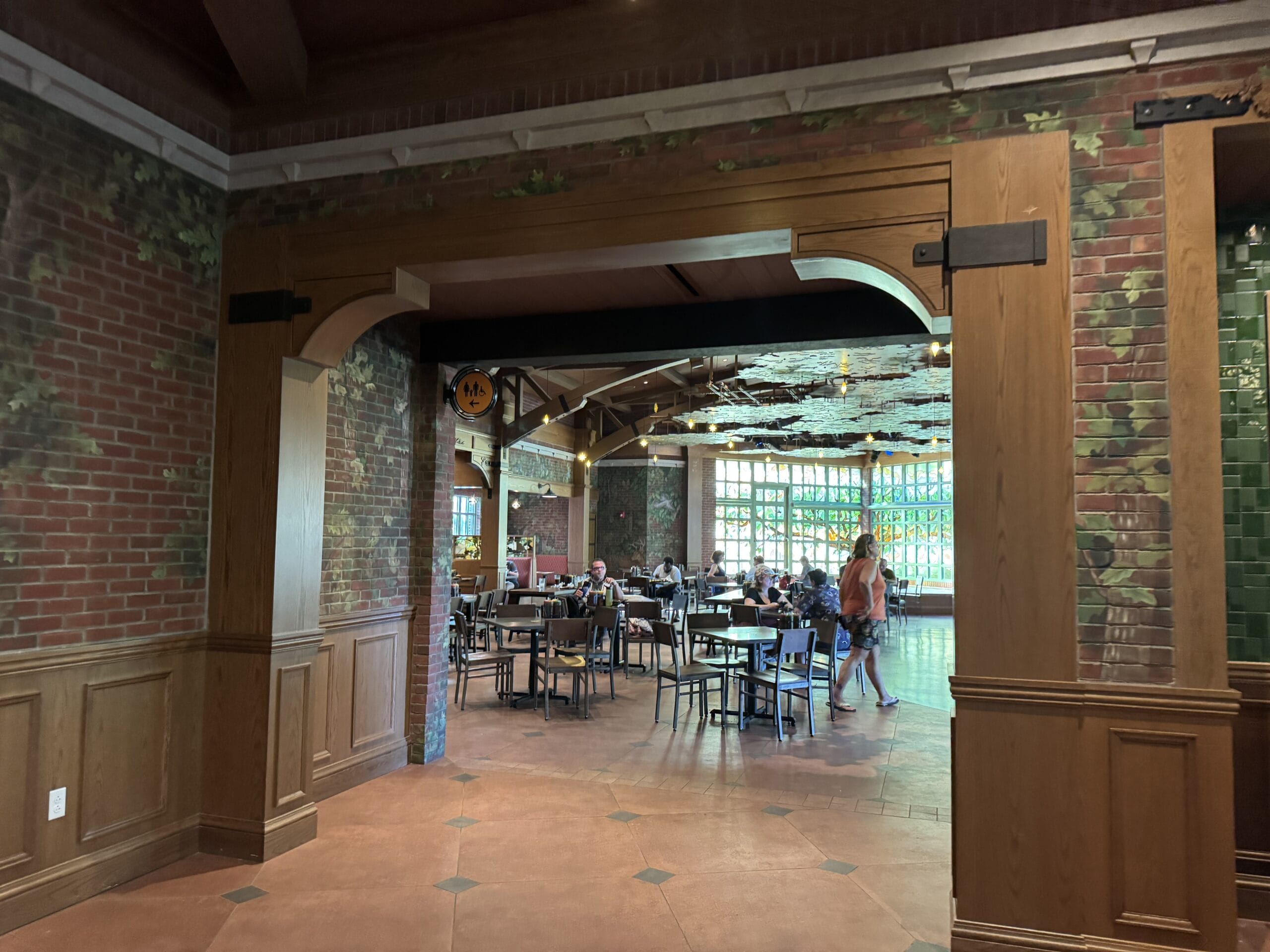 The Oak & Star Tavern, with wood accents and brick walls, resembles Disney park eateries where guests dine by bright, castle-like windows.