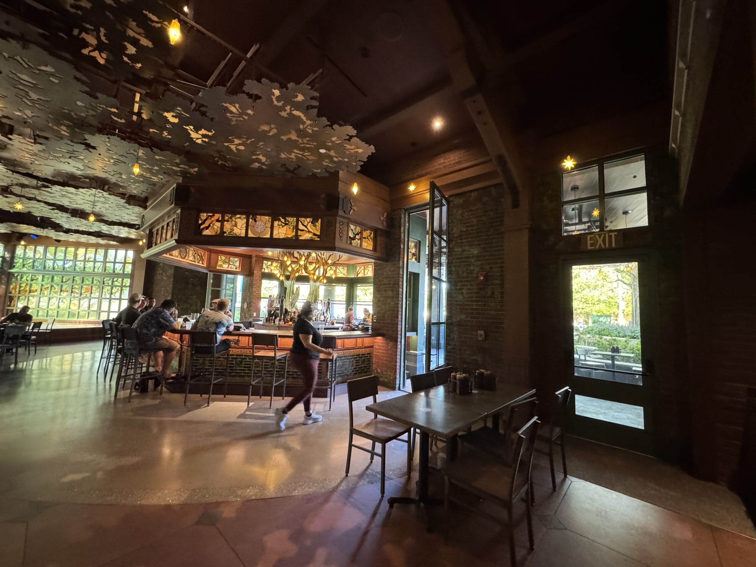 A woman passes by the bar at The Oak & Star Tavern, a cozy, warmly lit restaurant reminiscent of Main Street, U.S.A. décor.