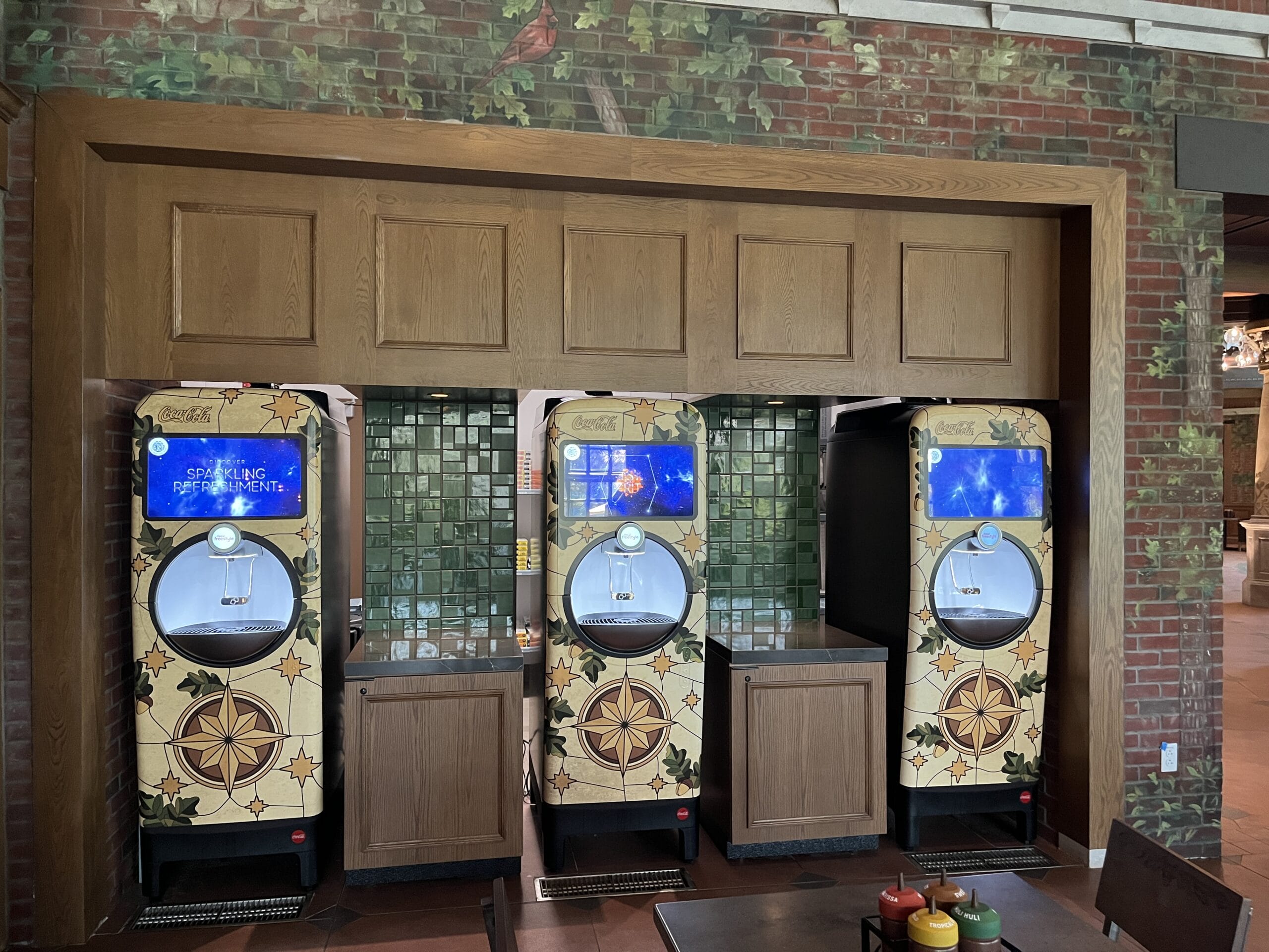 Three decorative Coca-Cola Freestyle machines at The Oak & Star Tavern in Walt Disney World, set against a green tiled wall.