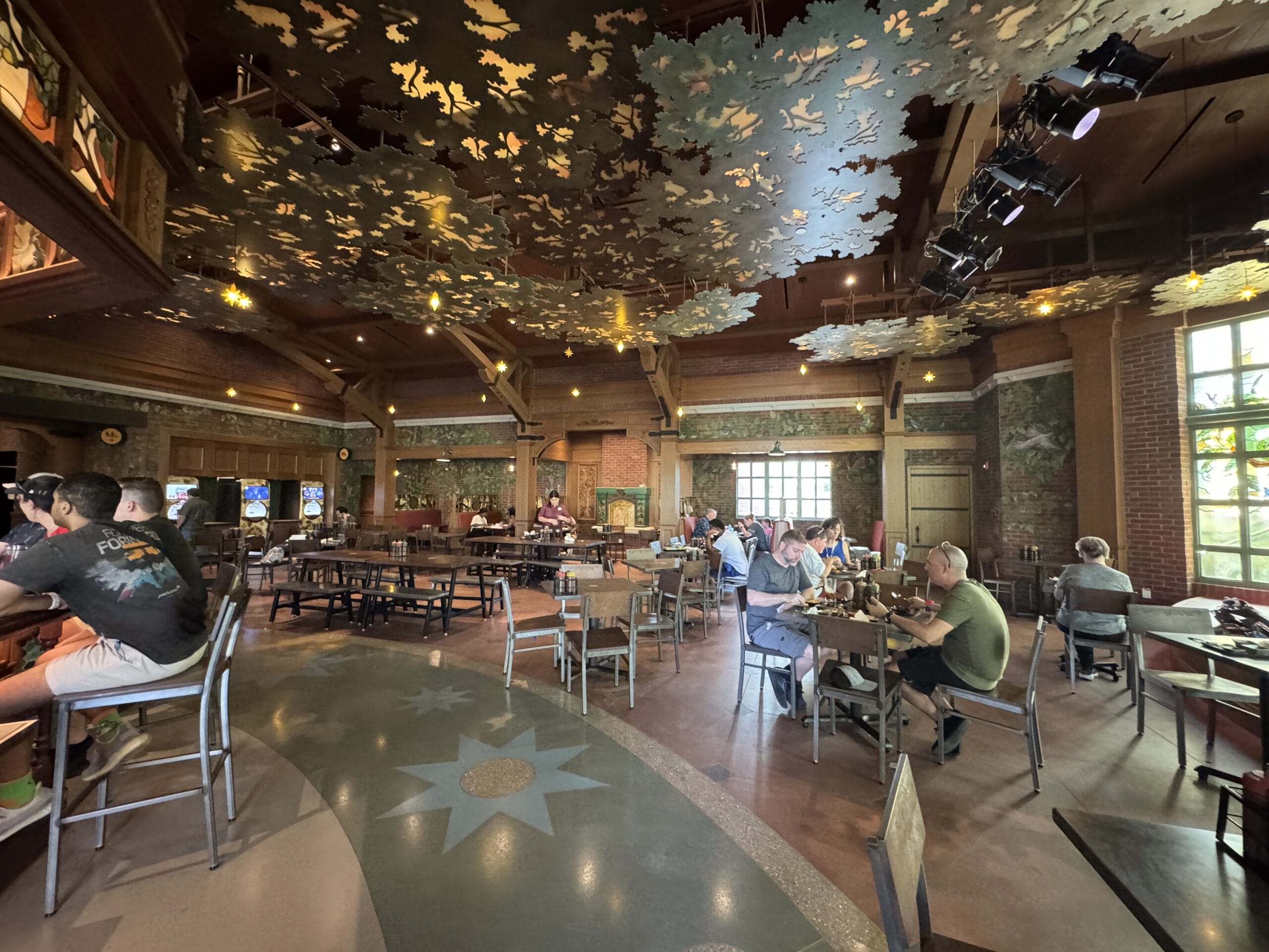 Spacious Oak & Star Tavern interior with wood decor and leafy ceiling, naturally lit—evokes Disney’s immersive, themed dining spaces.