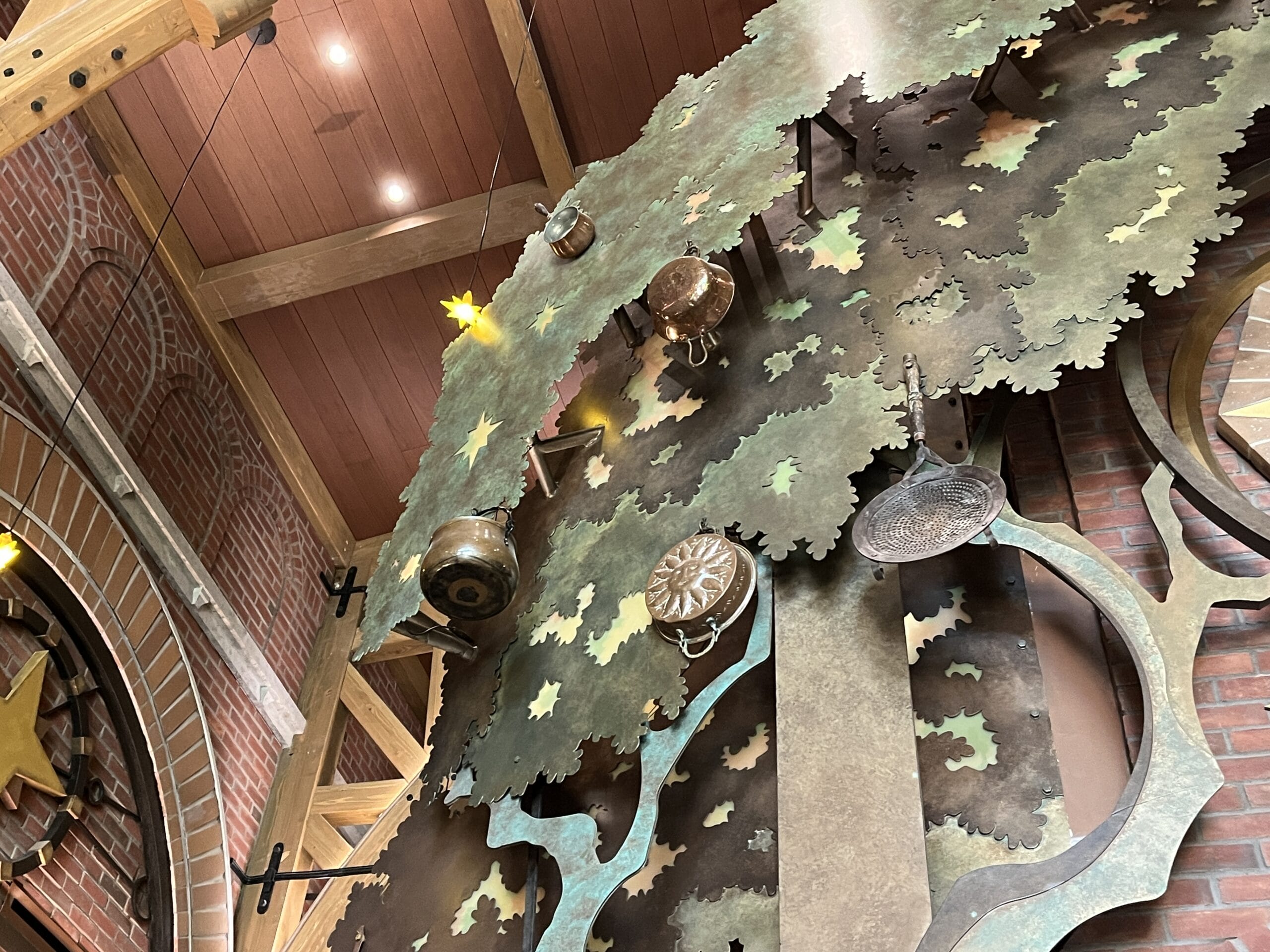 Metal cookware hangs from a large tree sculpture inside The Oak & Star Tavern, evoking rustic Disney park theming and décor.