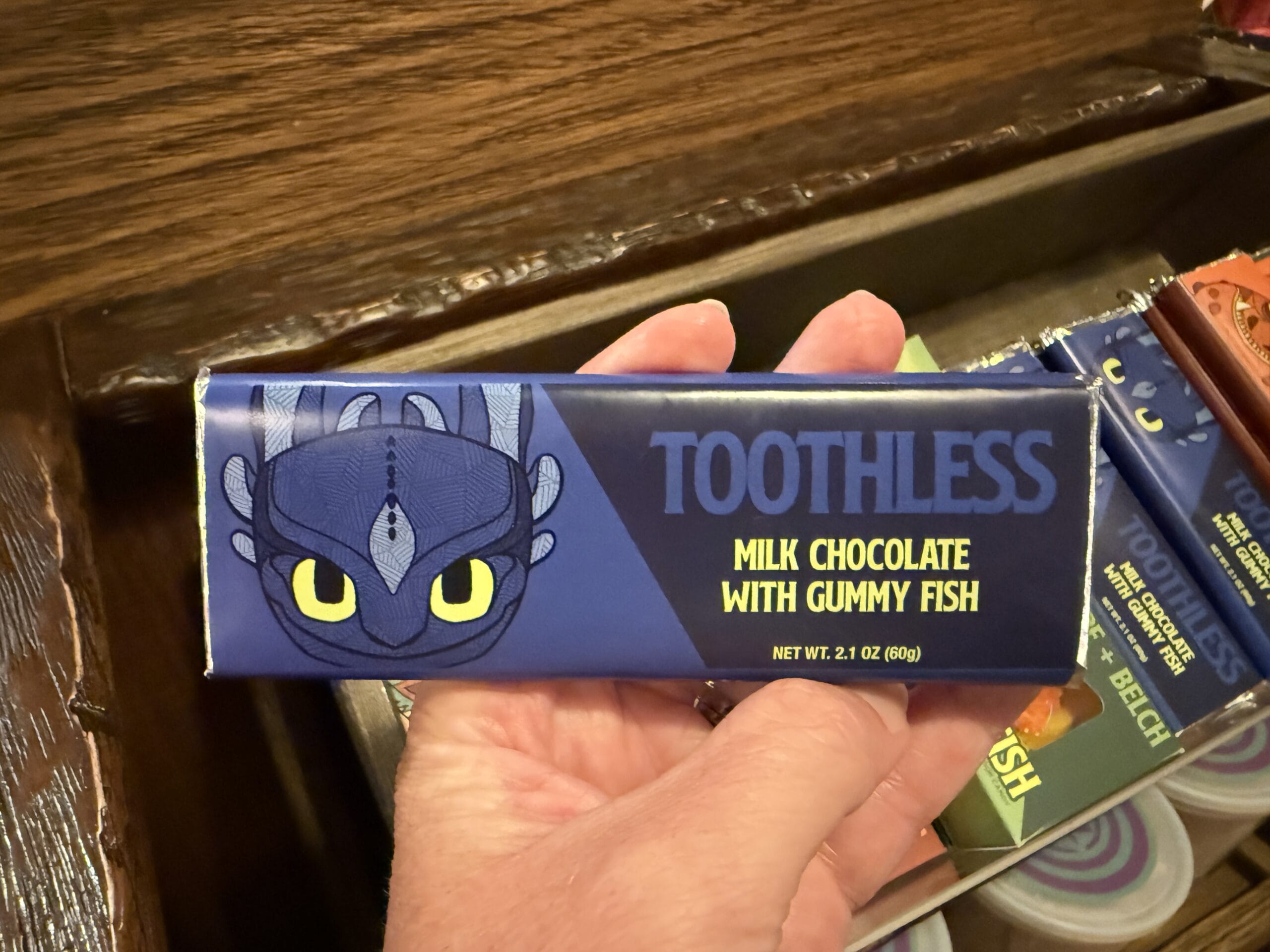 A Viking Traders hand holds a "Toothless" milk chocolate bar with gummy fish from How to Train Your Dragon.