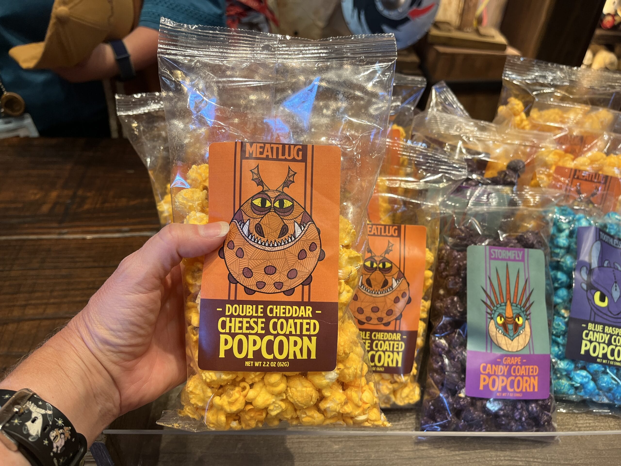 A hand holds a Viking Traders double cheddar popcorn bag featuring a cartoon monster on the label.