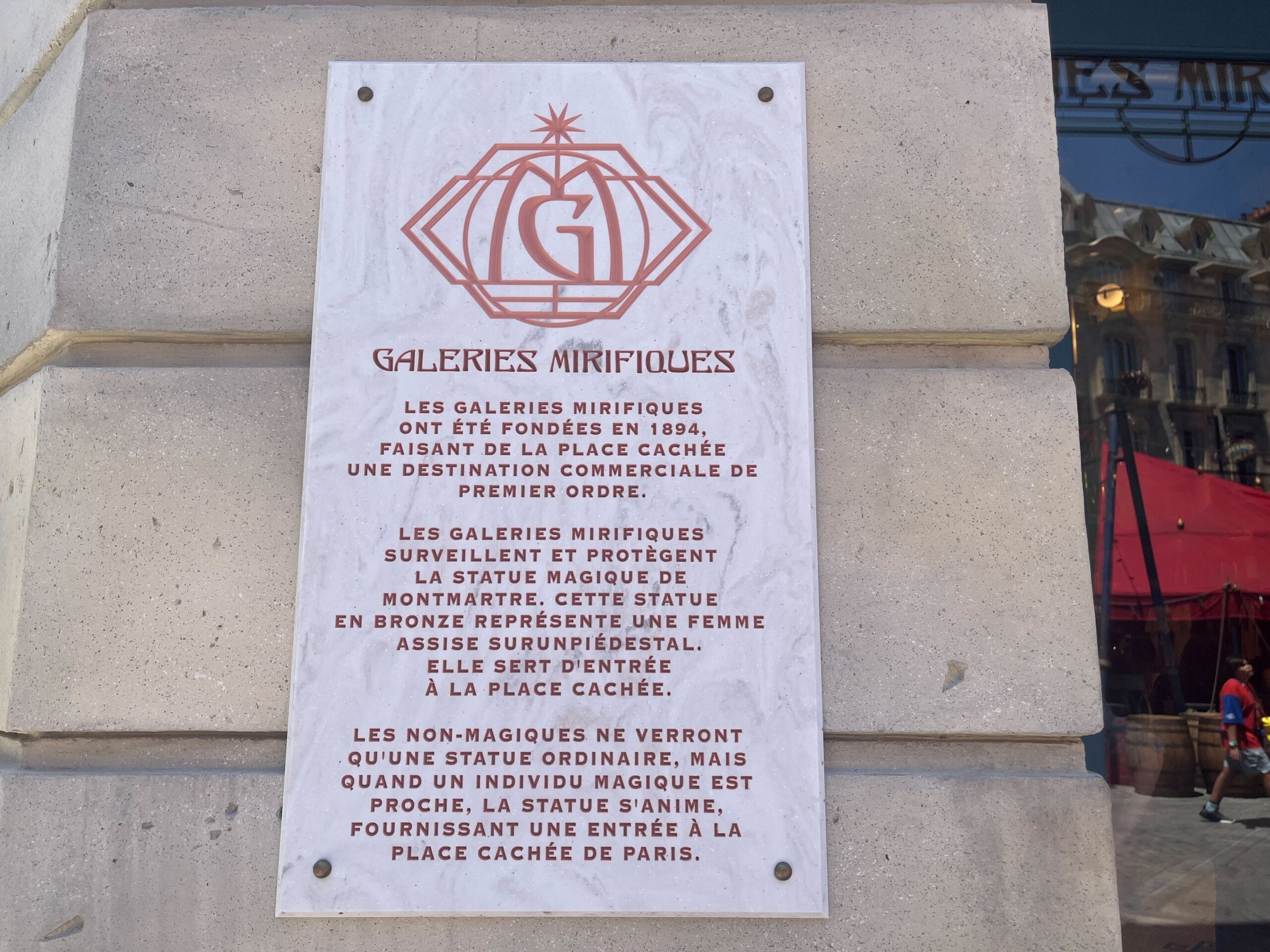 A plaque describes Les Galeries Mirifiques, hinting at a magical hidden statue and a secret Paris entrance.