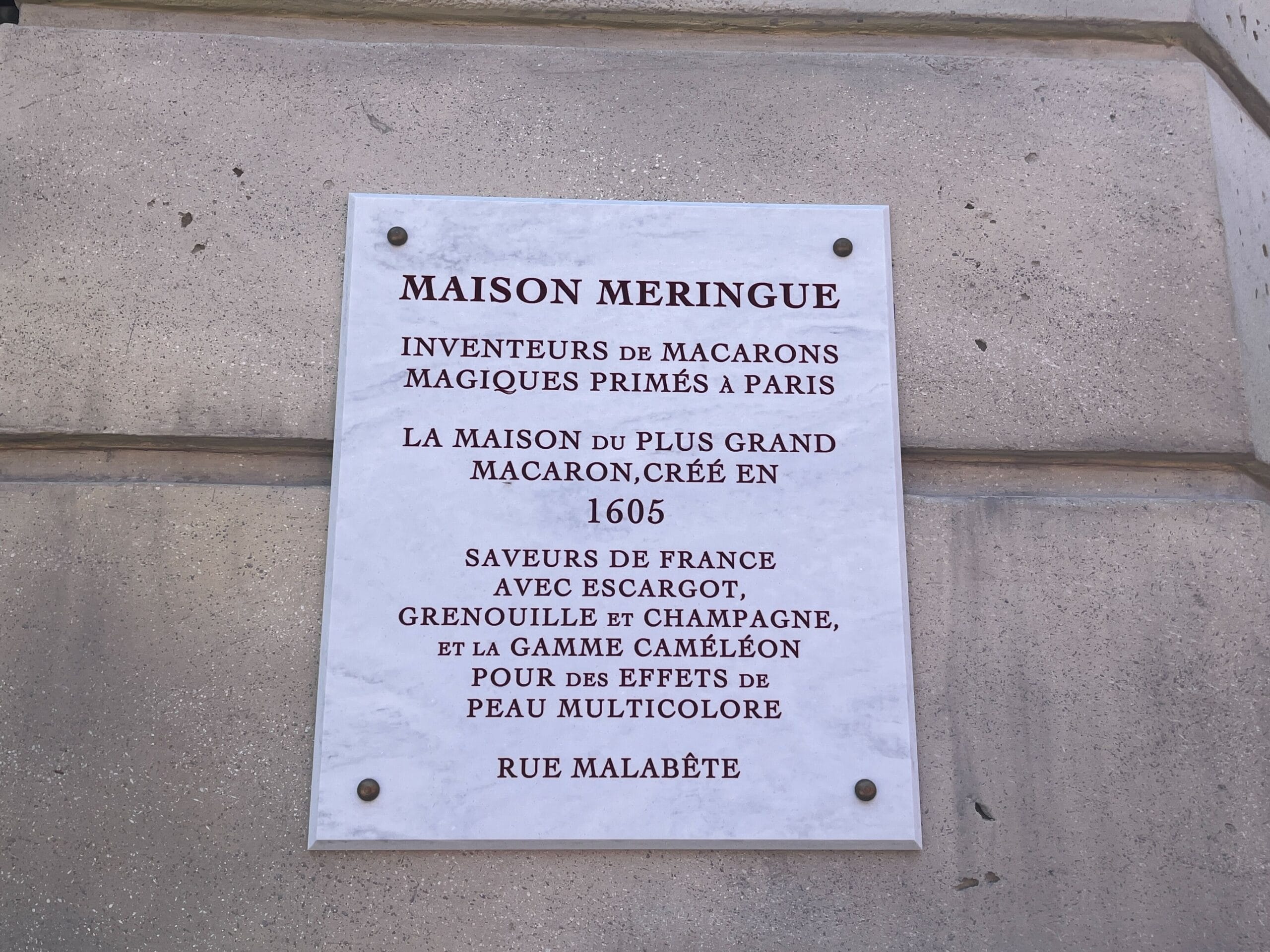 A marble plaque at Les Galeries Mirifiques honors Maison Meringue, Paris macaron inventors, established in 1605.