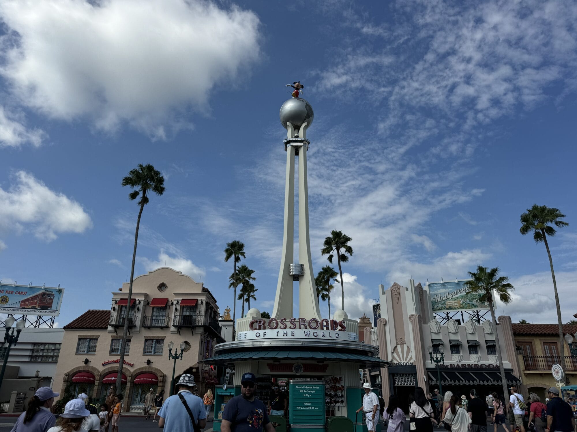 Art Deco-style Hollywood Studios Entrance tower with palm trees, crowds, and blue skies, perfect for visiting Hollywood Studios.