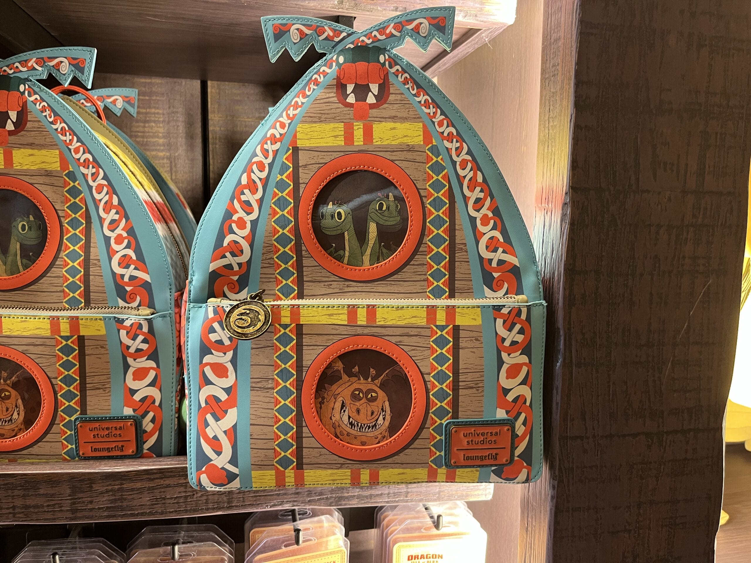 Decorative Viking-themed bag from Hiccup's Work Shop with cartoon dragons and an owl in circular windows on a store shelf.