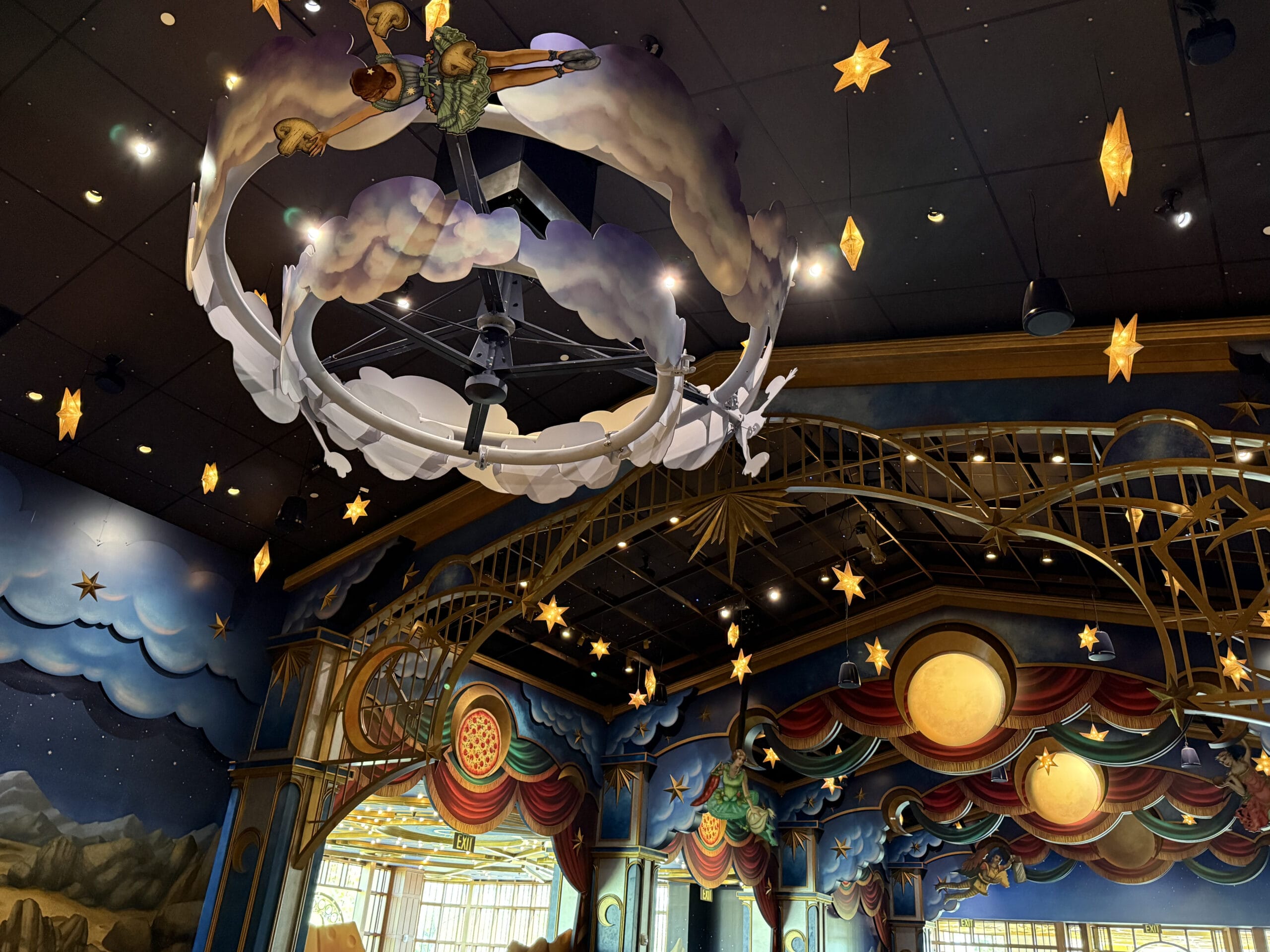 Colorful, whimsical ceiling decor at Celestial Park evokes a playful, theatrical nighttime sky scene with stars and planets.