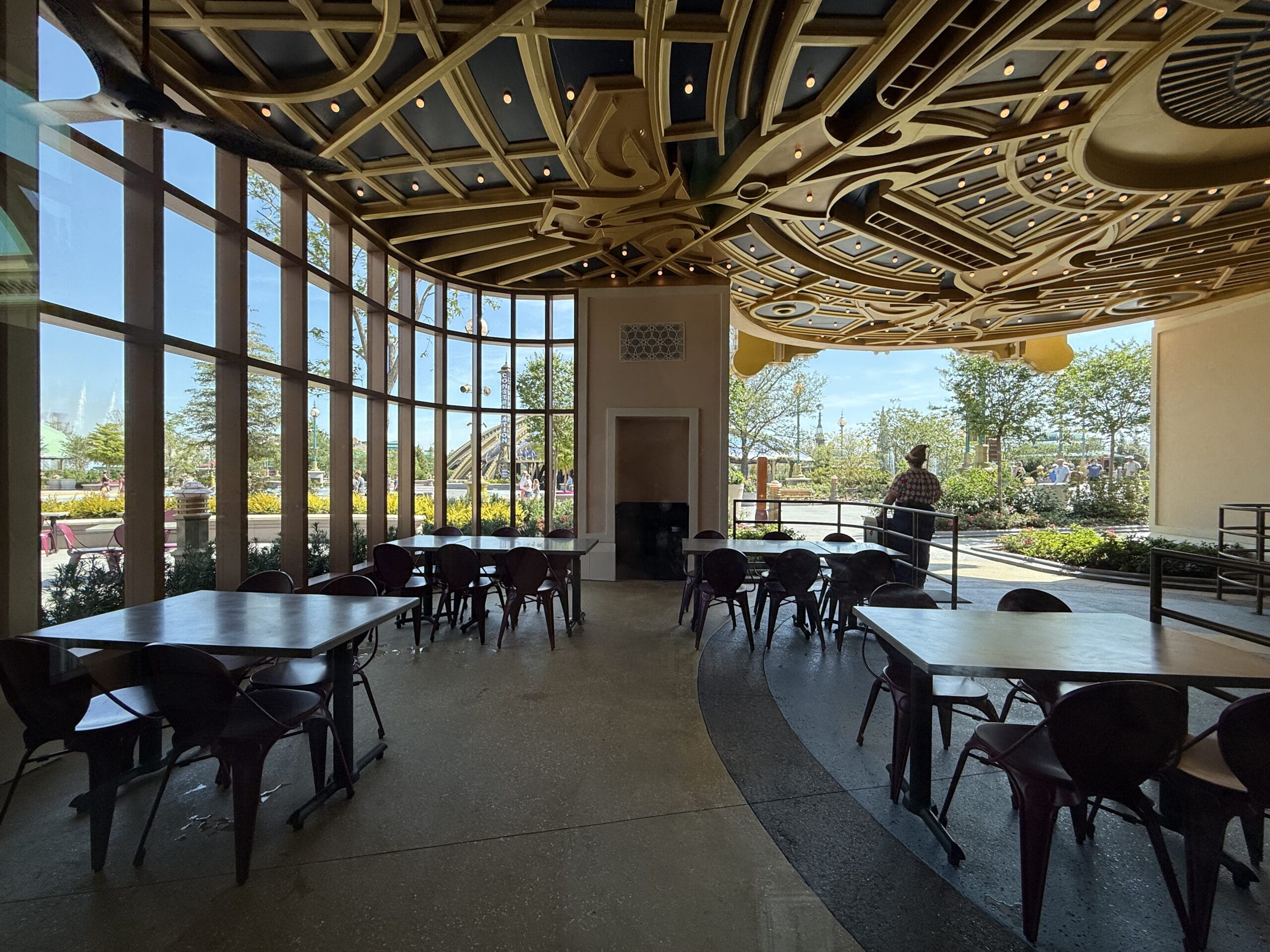 Spacious café with empty tables, ornate ceiling, and garden view; reminiscent of Celestial Park’s Pizza Moon Restaurant.