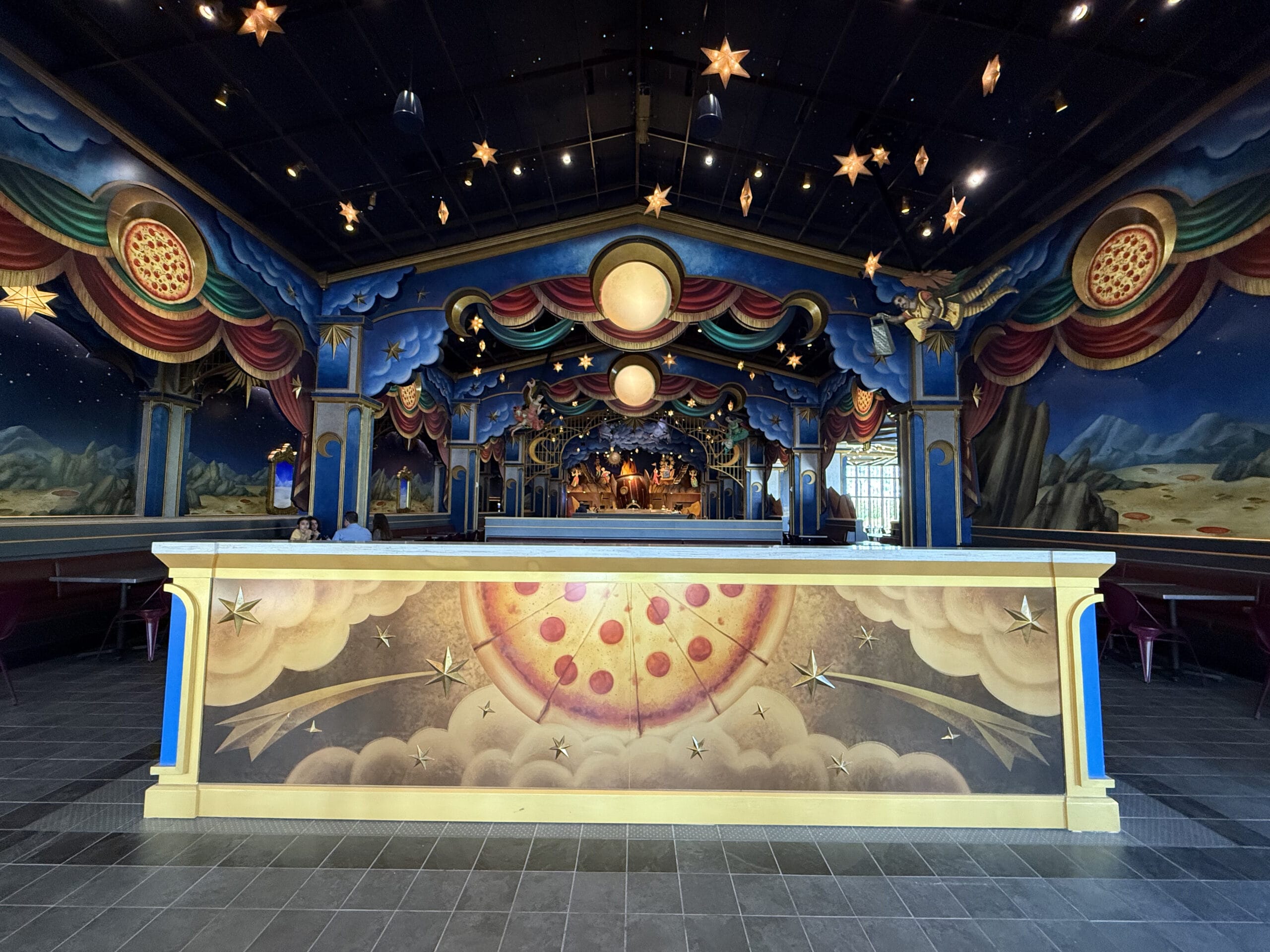 Colorful, star-themed stage at Celestial Park with circus décor, painted backdrop, and celestial motifs on the walls.