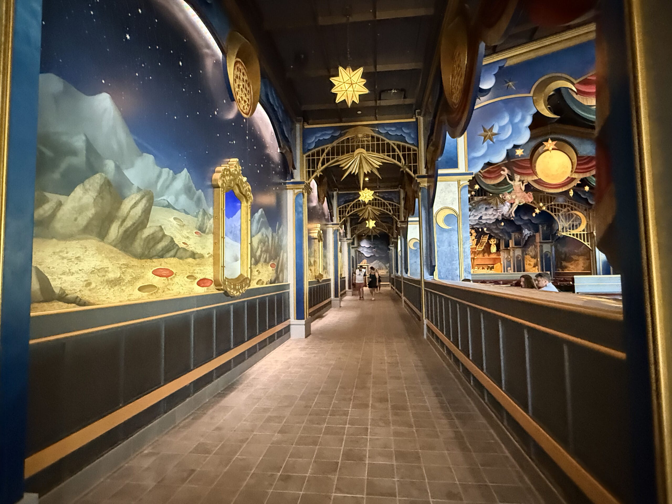 A whimsical hallway at Pizza Moon Restaurant features starry ceilings, colorful murals, and ornate decor in Celestial Park.