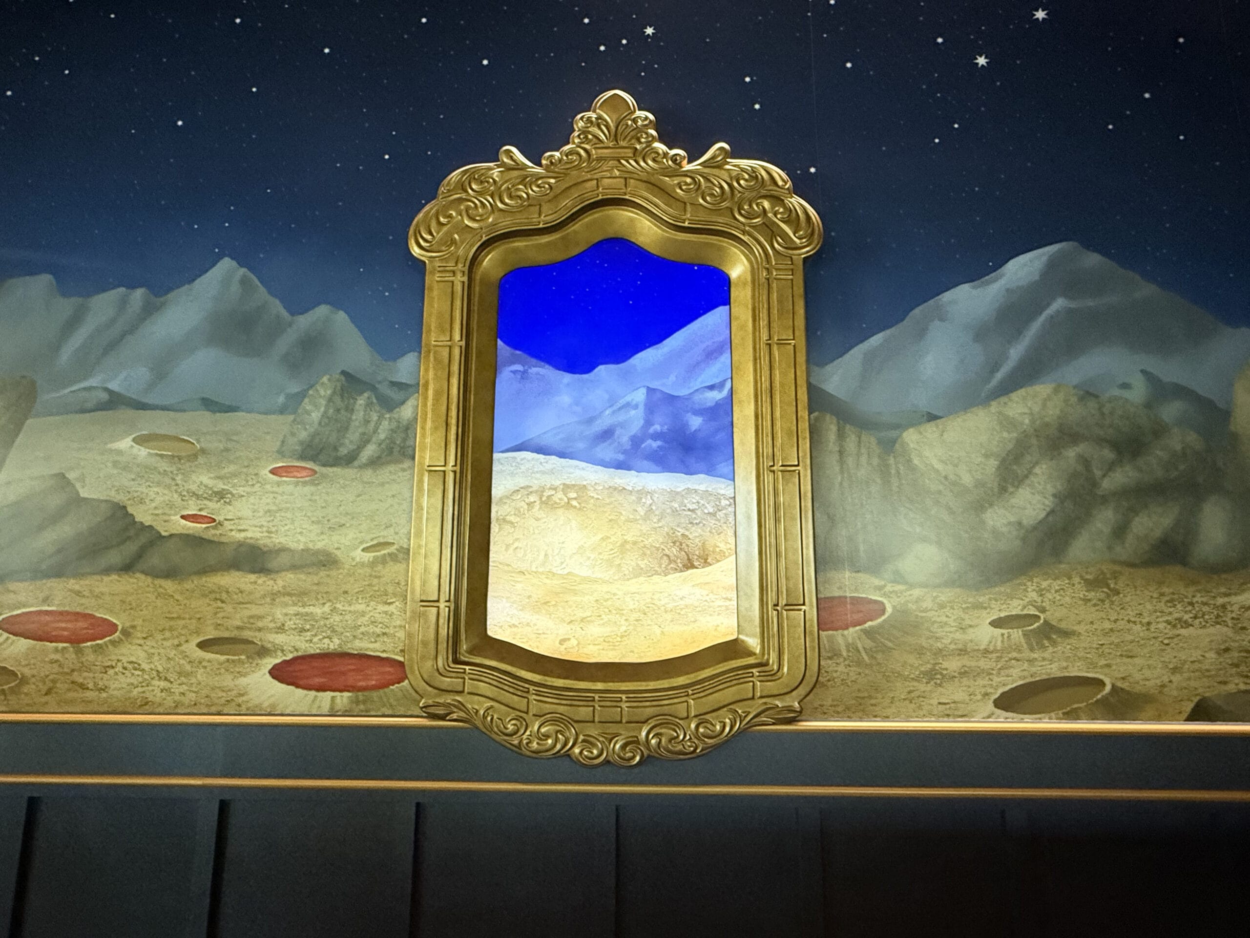 A gold ornate mirror frame set against a mural of Celestial Park mountains and a starry sky, blending into the landscape.