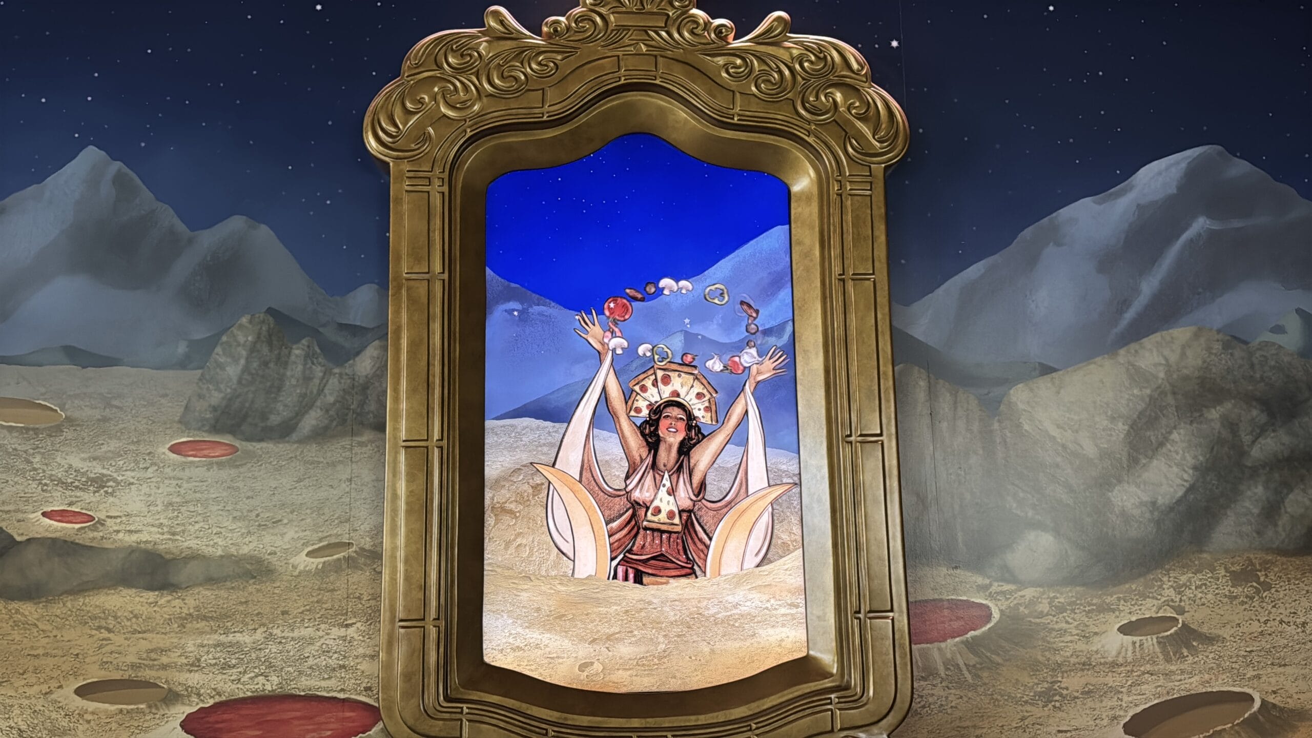 A framed painting shows a woman in ornate clothing rising from sand in Epic Universe’s Celestial Park, arms raised.