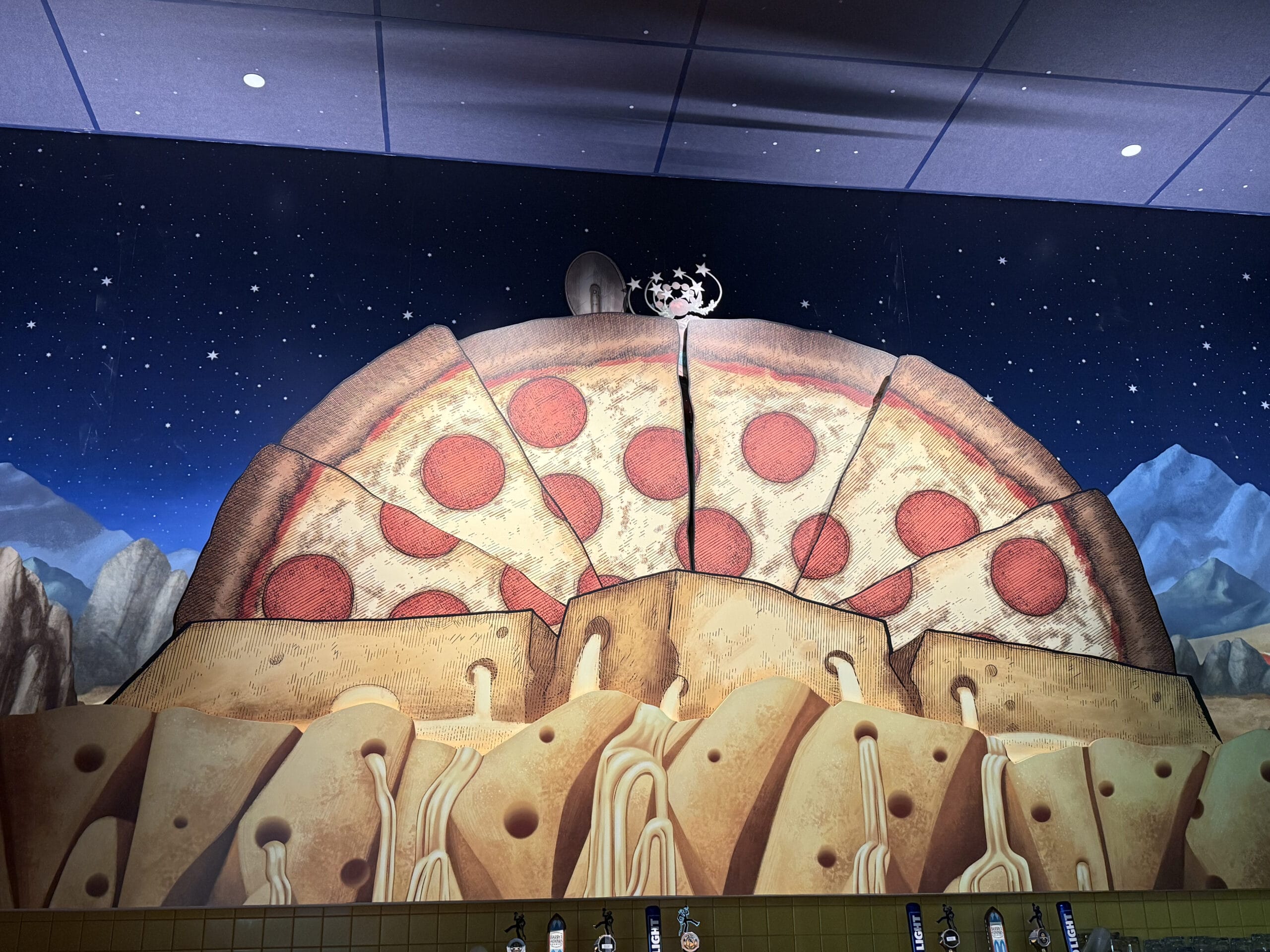 A mural of a giant pizza with pepperoni at Pizza Moon Restaurant, glowing under a starry night in Celestial Park.
