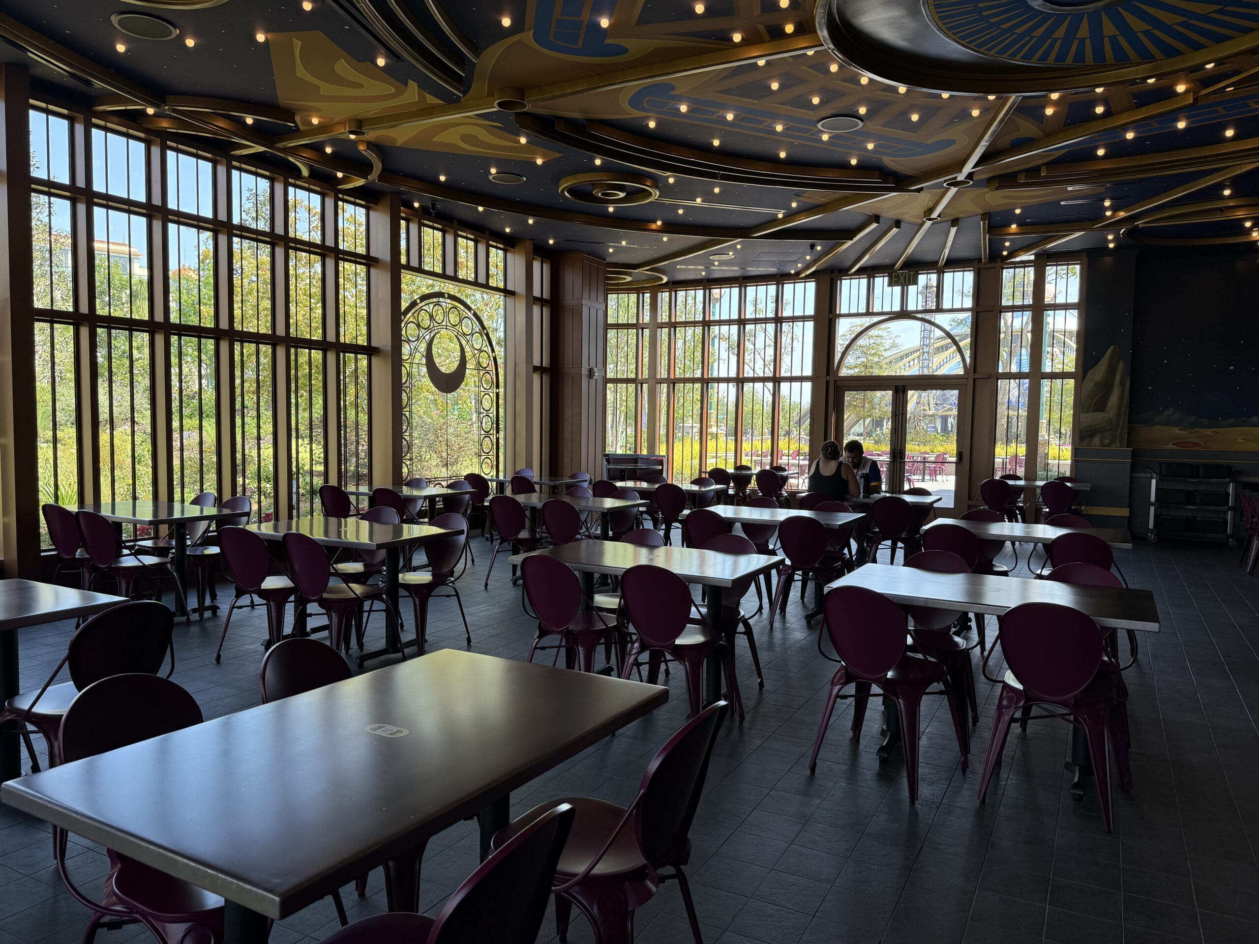 A spacious, modern dining area at Pizza Moon Restaurant with purple chairs and cosmic-themed ceiling decor.