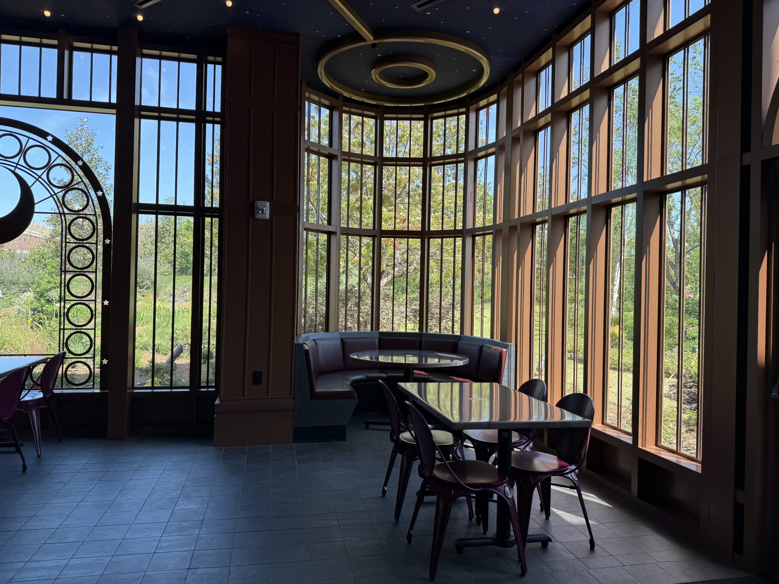 Sunlit café with curved windows and round booth, overlooking Celestial Park—perfect for a Pizza Moon Restaurant experience.