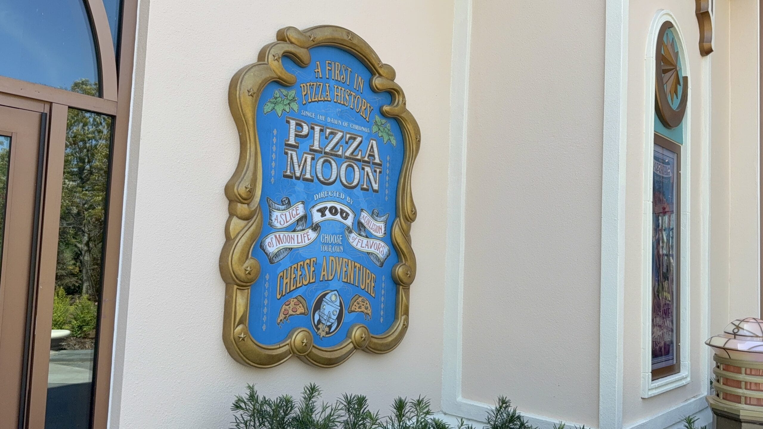 A decorative sign at Pizza Moon Restaurant in Celestial Park reads "Pizza Moon: A Fieri Pizza History, Cheese Adventure.
