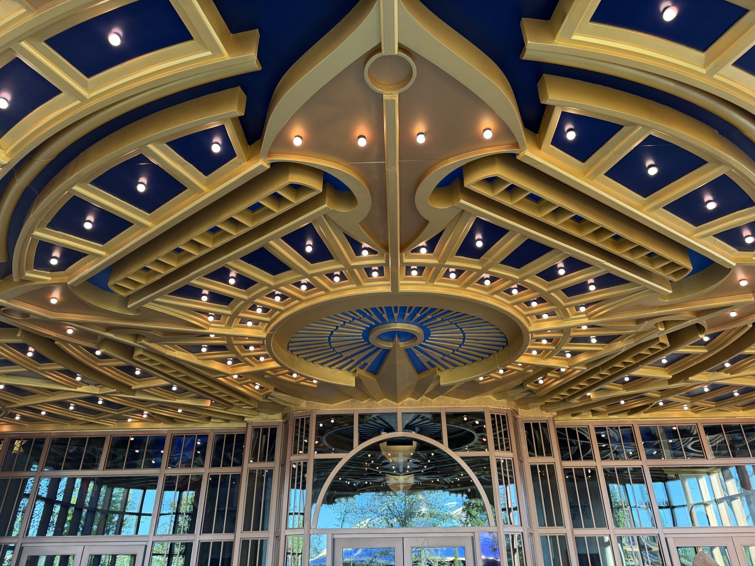 Gold and blue ornate ceiling with lights crowns the Pizza Moon Restaurant entrance at Celestial Park, Epic Universe.