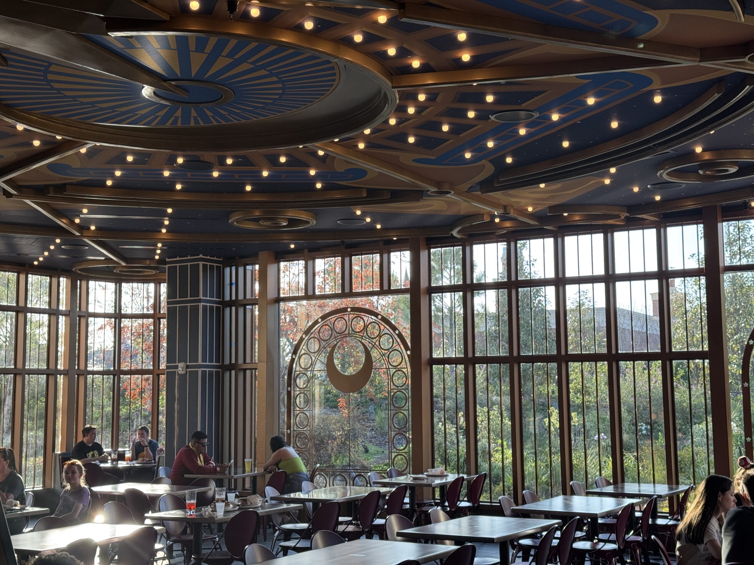 A sunlit dining area with large windows, star-lit ceiling, and Pizza Moon Restaurant’s crescent moon glass door.