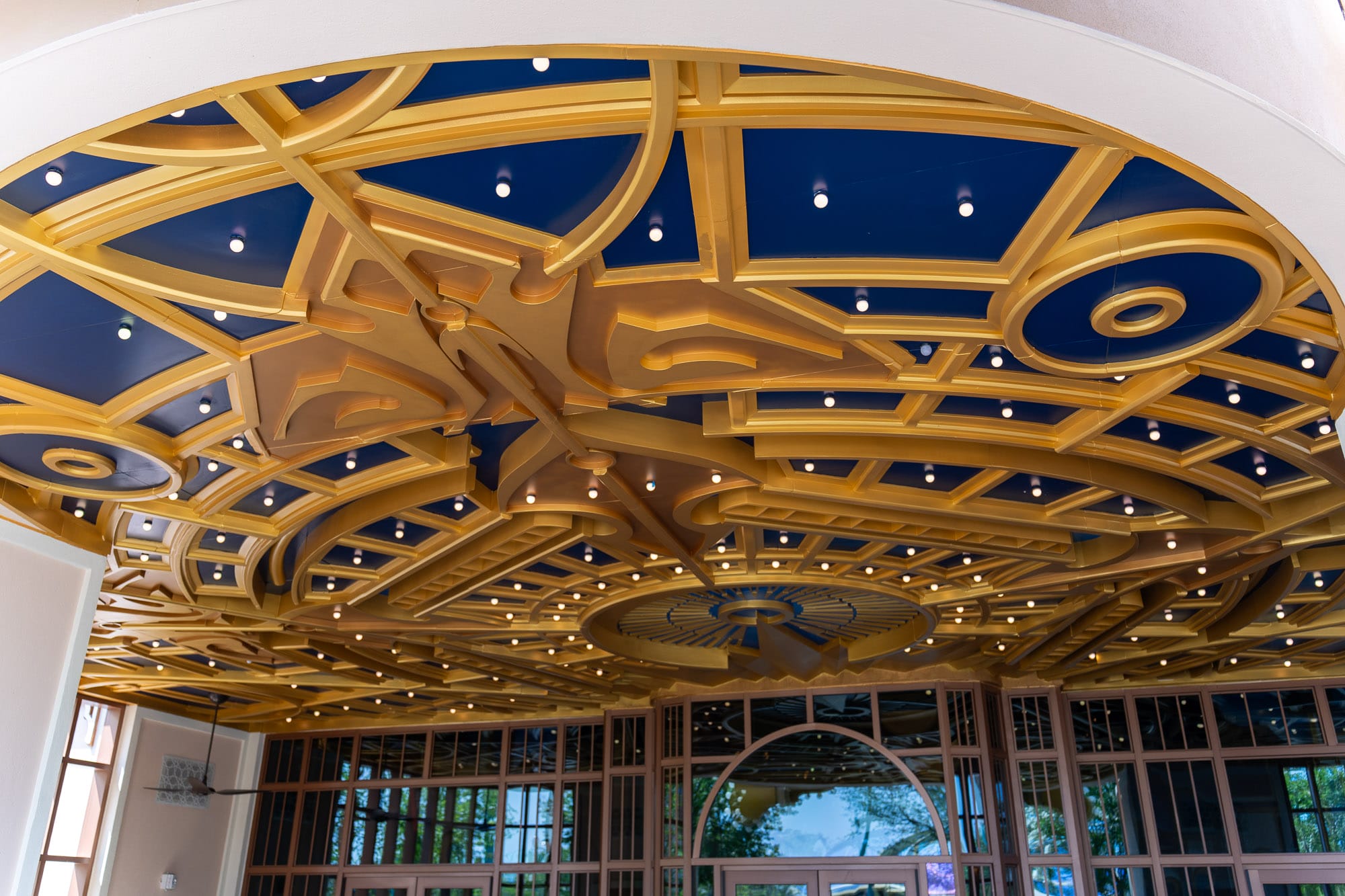 Decorative gold and navy blue ceiling with geometric patterns at Epic Universe’s Celestial Park, above Pizza Moon Restaurant.