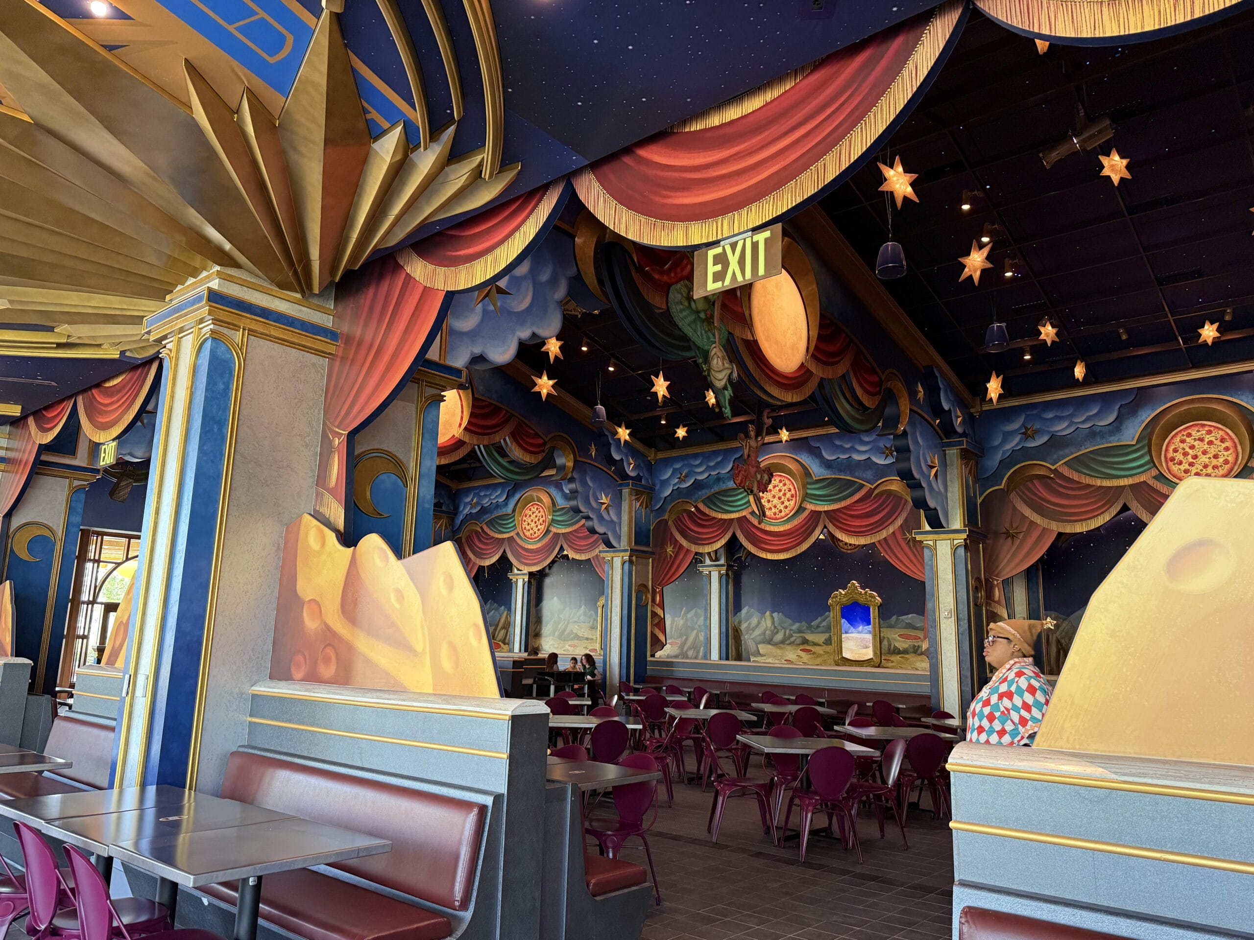 A vibrant, space-themed Pizza Moon Restaurant with star murals and red chairs awaits at Celestial Park.